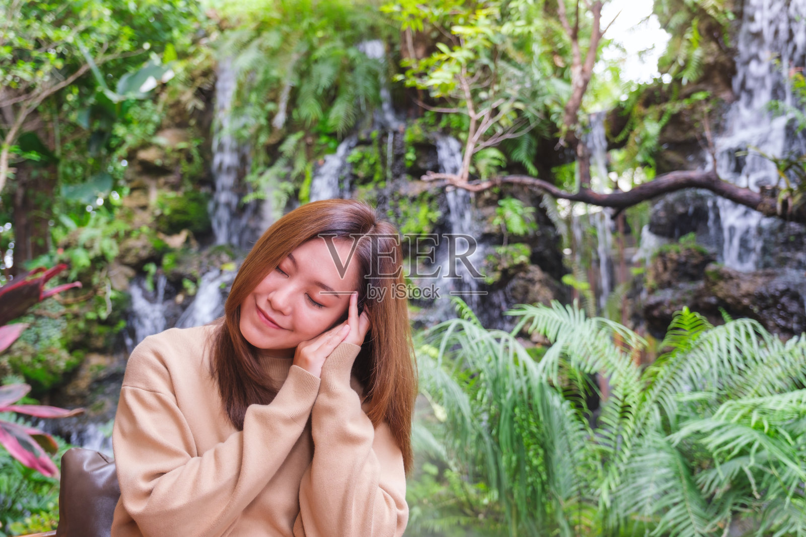 一个年轻女子闭着眼睛坐在花园里放松的肖像照片摄影图片
