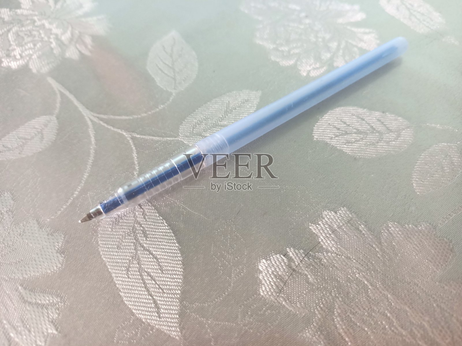 笔的背景上有美丽的花卉图案。蓝色的钢笔。照片摄影图片