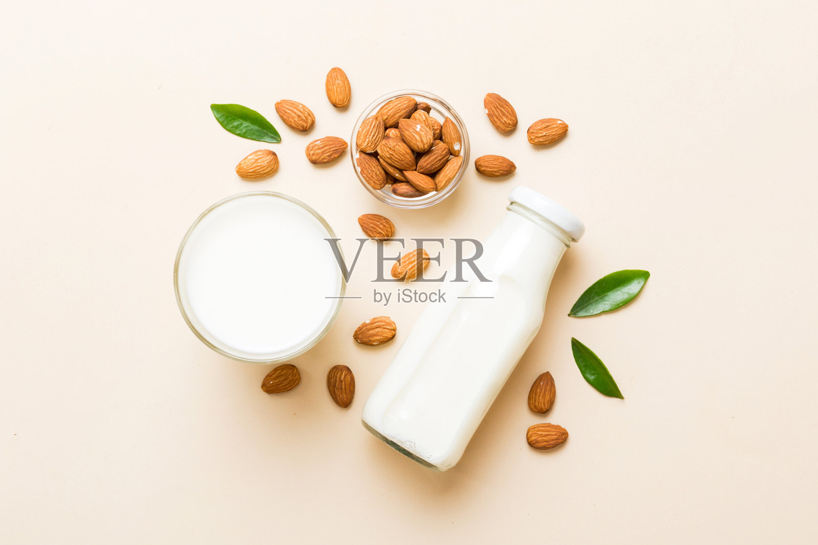 玻璃瓶子里的杏仁奶的俯视图,彩色的桌子上有杏仁坚果。带拷贝空间的俯视图照片摄影图片