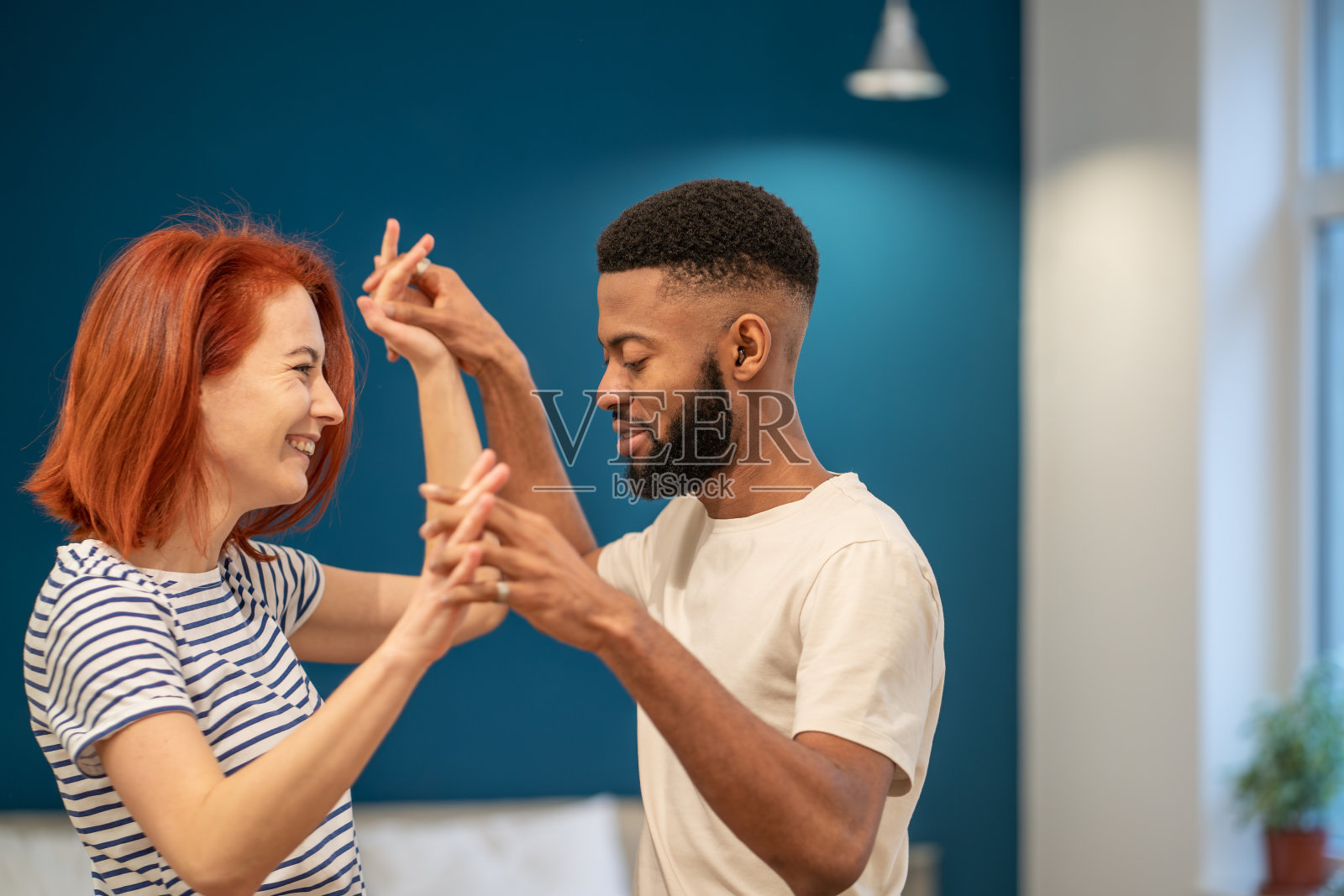 爱的年轻多样的夫妇在现代卧室与全景窗户浪漫舞蹈。照片摄影图片