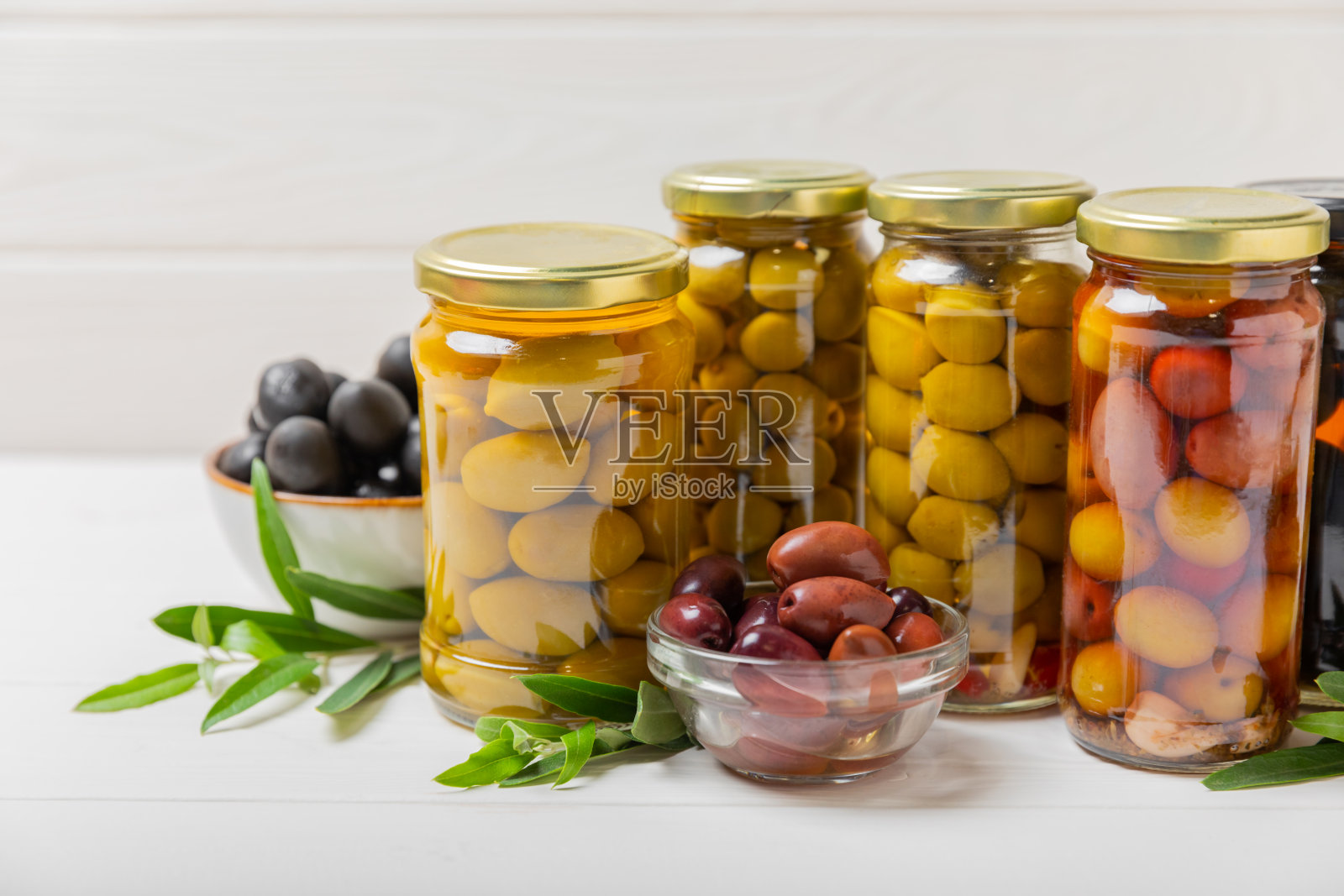 橄榄装在玻璃罐里,背景是混凝土。罐子里去核的橄榄。玻璃罐里的腌橄榄。在木制背景上。腌橄榄。文本空间。拷贝空间。素食食物。照片摄影图片