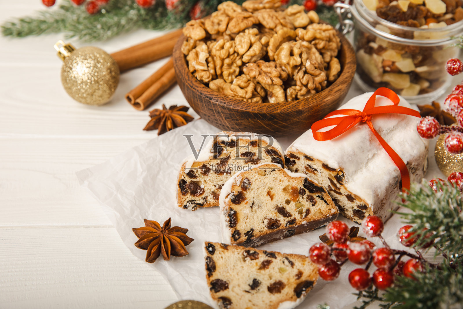 圣诞礼物——传统的德国面包放在摆着冷杉树枝的棕色木桌上。由生面团、坚果和杏仁饼撒上糖粉制成的节日甜点。副本的空间。放文字的地方。照片摄影图片