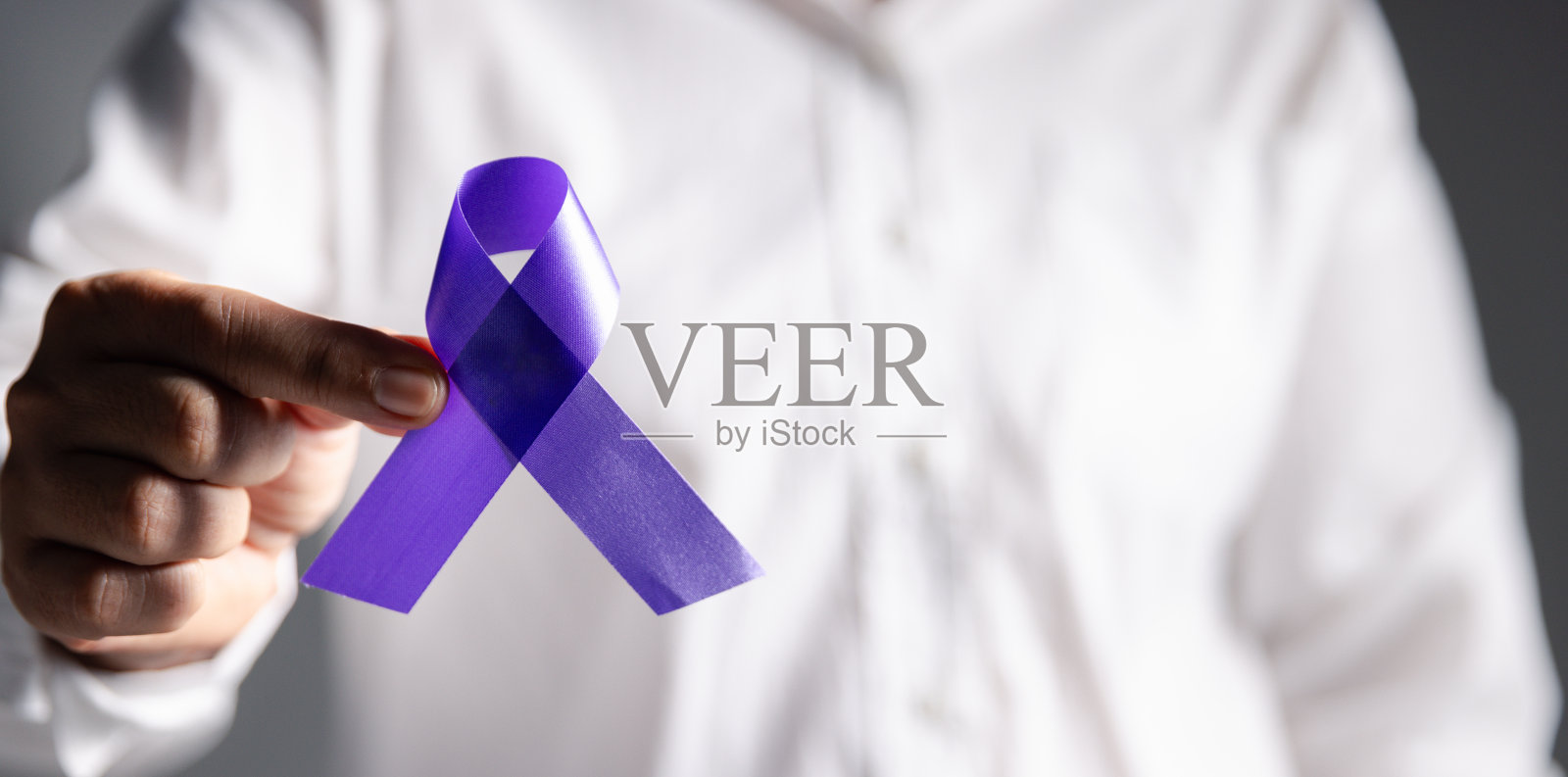 灰色背景上带紫色丝带的女人,特写为文字留出空间。家庭暴力意识。紫丝带支持人们的生活。保健和世界癌症日概念。照片摄影图片