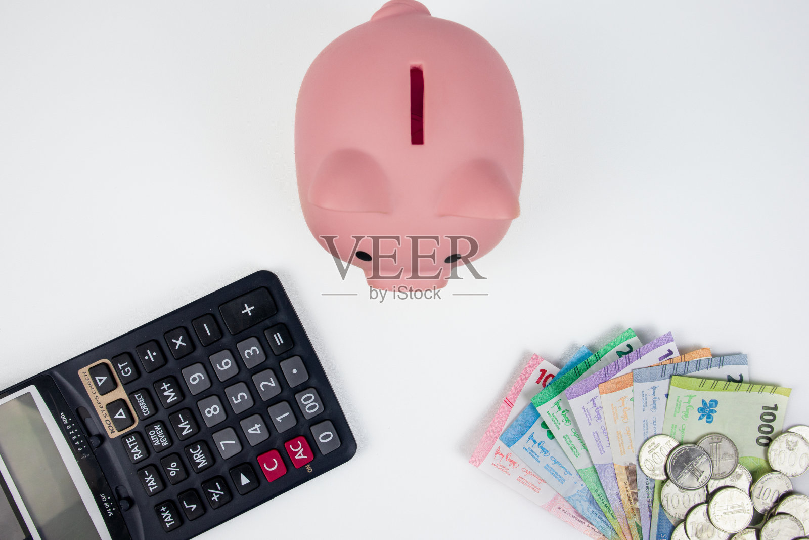 有存钱罐、笔记本、计算器和一堆印尼货币的金融概念照片摄影图片