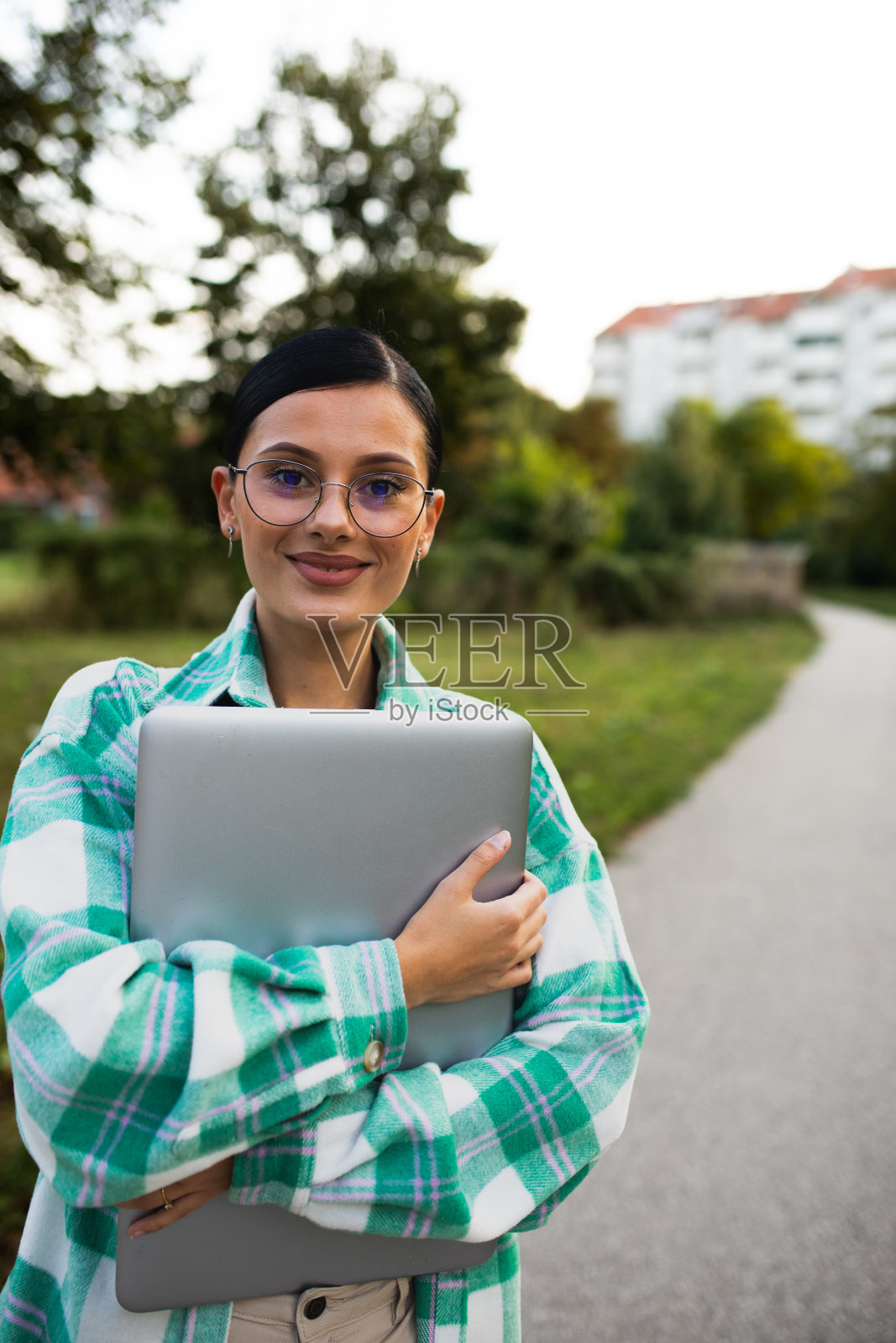 一个年轻女子的画像,手里拿着一台笔记本电脑照片摄影图片