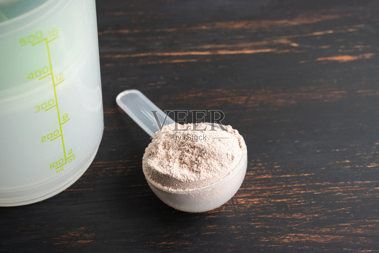乳清巧克力蛋白粉在一个塑料测量勺在一个黑暗的木制背景照片摄影图片