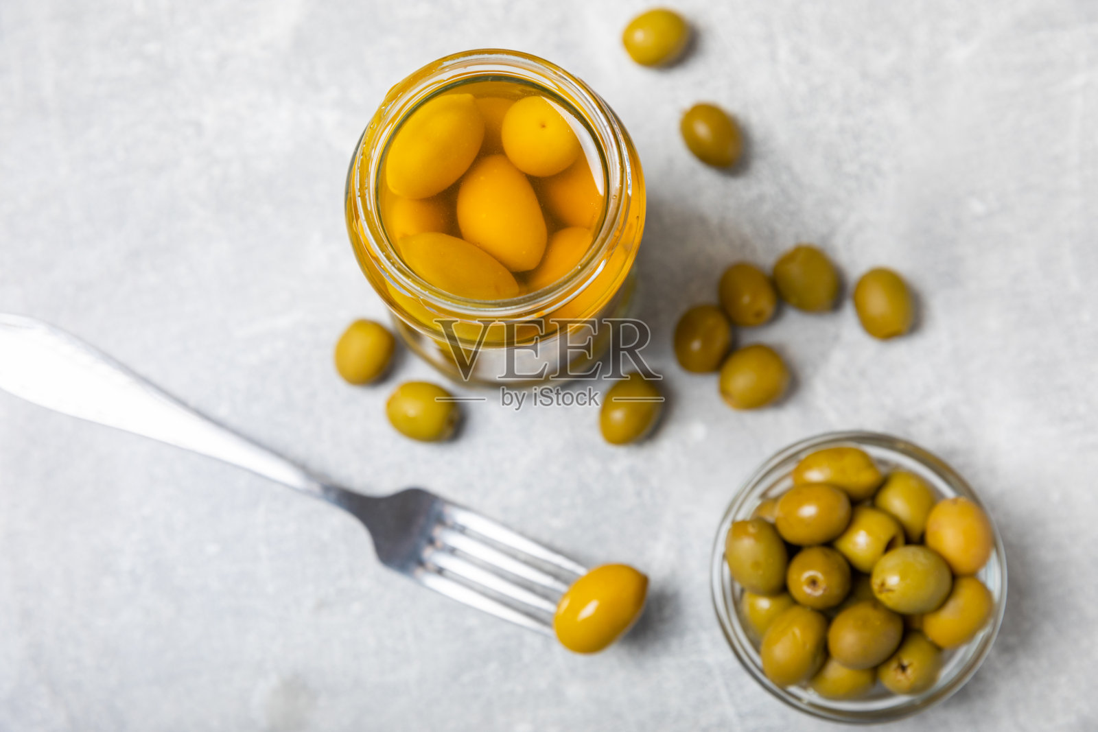 橄榄装在玻璃罐里,背景是混凝土。罐子里去核的橄榄。玻璃罐里的腌橄榄。在木制背景上。腌橄榄。文本空间。拷贝空间。素食食物。照片摄影图片