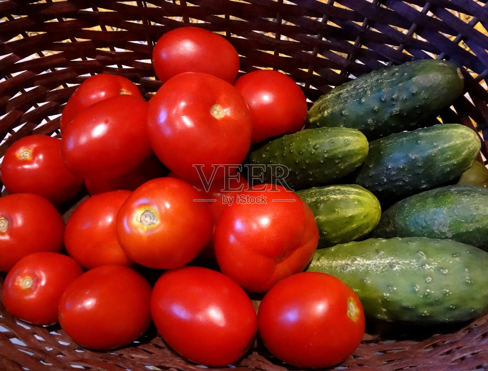 柳条篮子里的红西红柿和绿黄瓜照片摄影图片