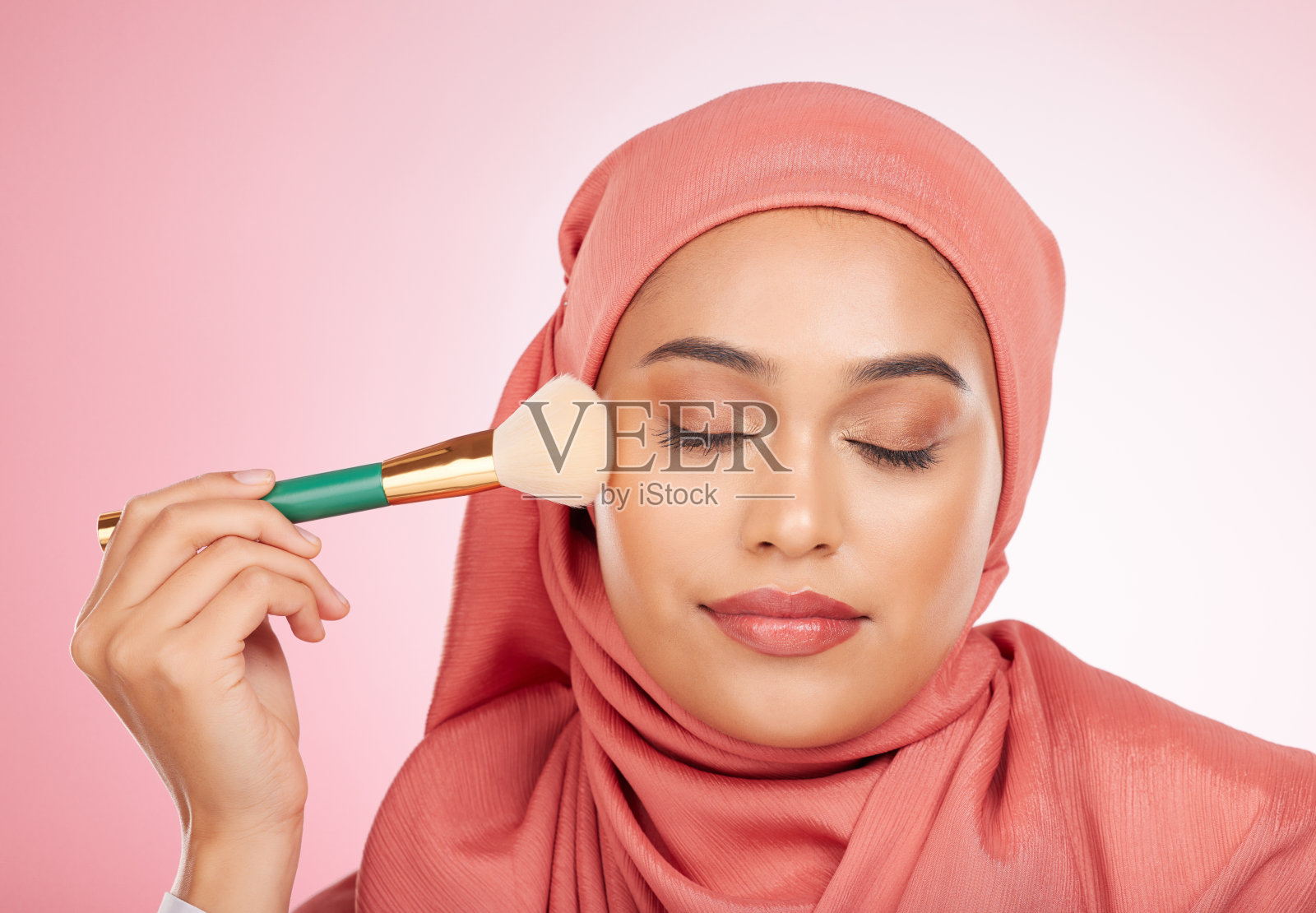 化妆,化妆刷和穆斯林妇女放松从化妆品和自我护理的工作室。面部,光彩和健康的女性与美容,皮肤护理和光泽与头巾和皮肤工具的脸照片摄影图片