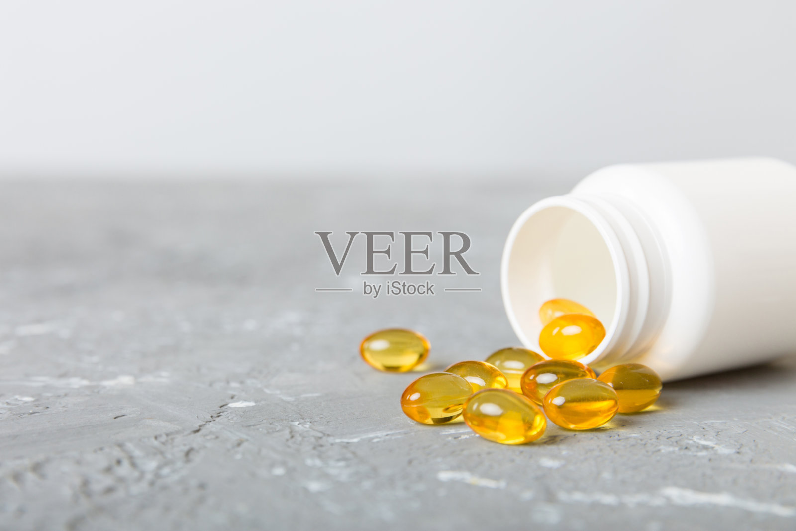 软凝胶药丸与欧米伽-3油溢出药瓶特写。凝胶胶囊瓶表面白色。欧米茄3,多种维生素,钙,抗生素。健康。免疫力照片摄影图片