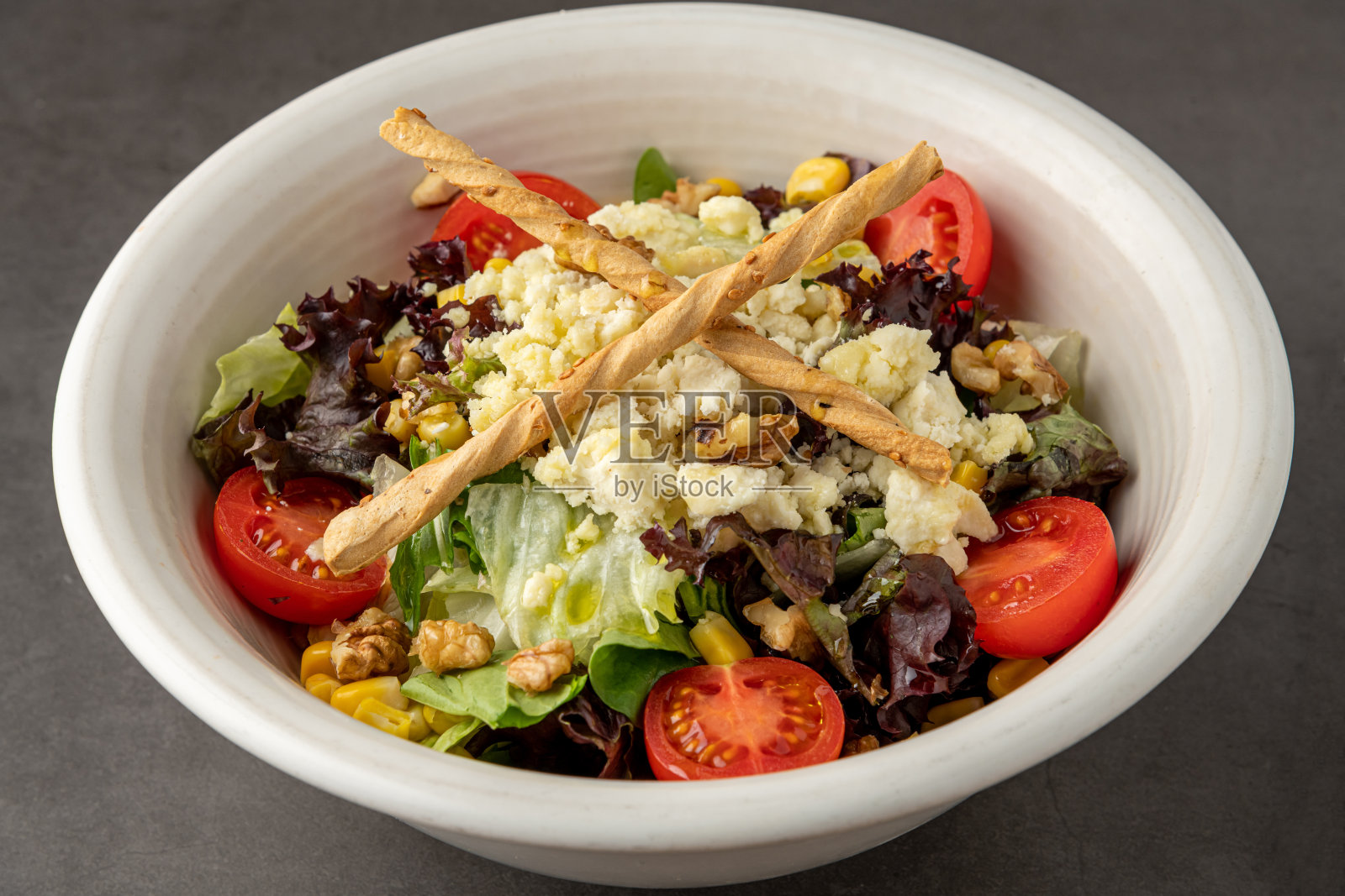 石桌上白瓷碗里的地中海沙拉配山羊奶酪照片摄影图片