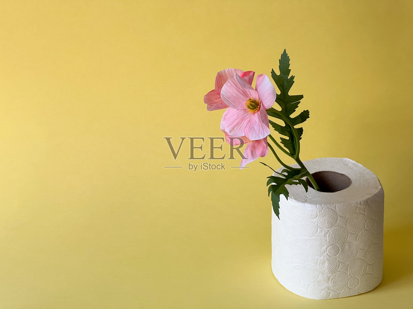 白色的卫生纸和黄色背景上的一朵粉红色的花。卫生照片摄影图片