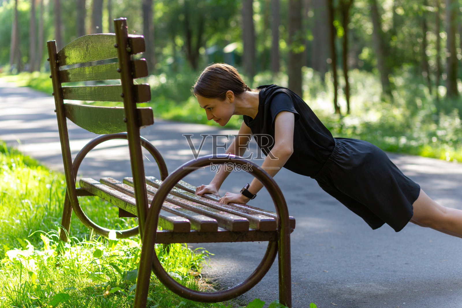 漂亮的年轻运动女性穿着黑色t恤,黑色短裤和粉色运动鞋,锻炼肱三头肌和胸部照片摄影图片