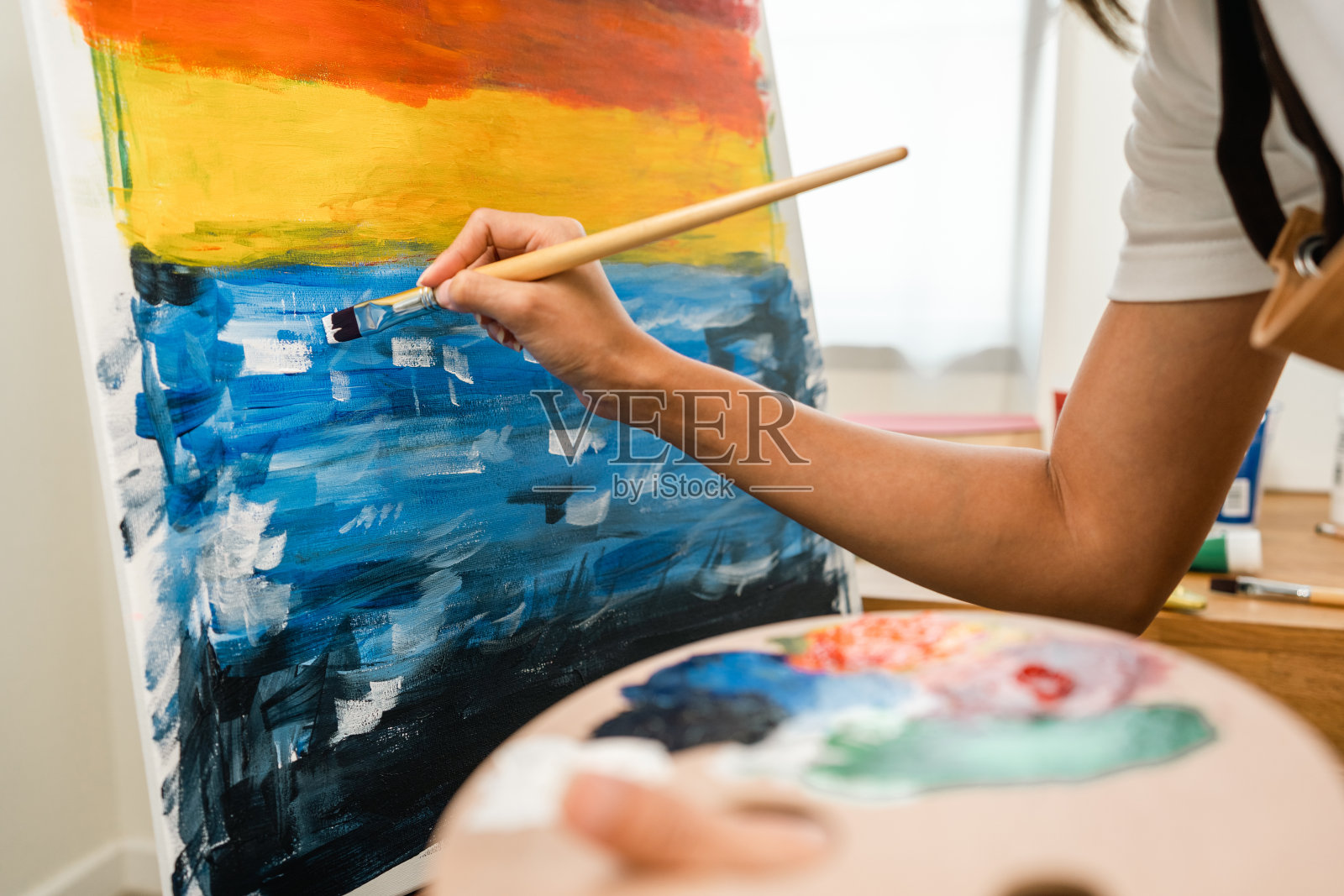 近距离的手亚洲女艺术家正在用画笔和不同的丙烯酸颜料绘画。作为艺术概念的女艺术家在创作工作室的画布上作画照片摄影图片