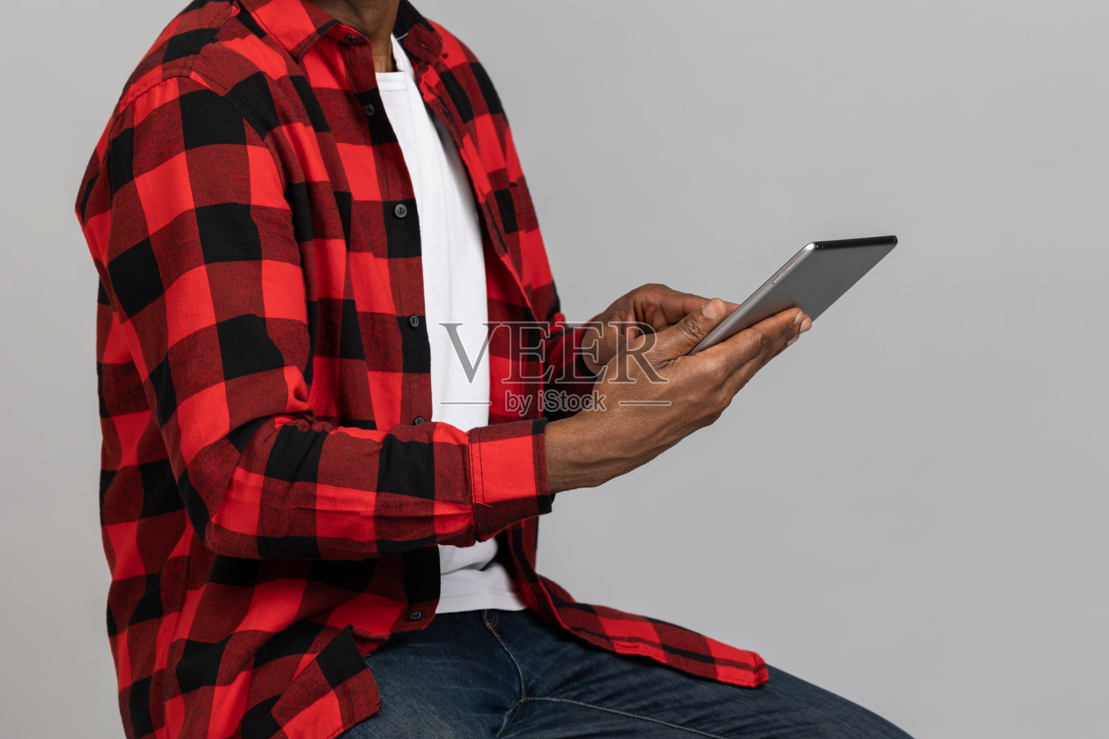 难以辨认的黑胡子男子穿着红色格子衬衫,正在使用数码平板电脑照片摄影图片
