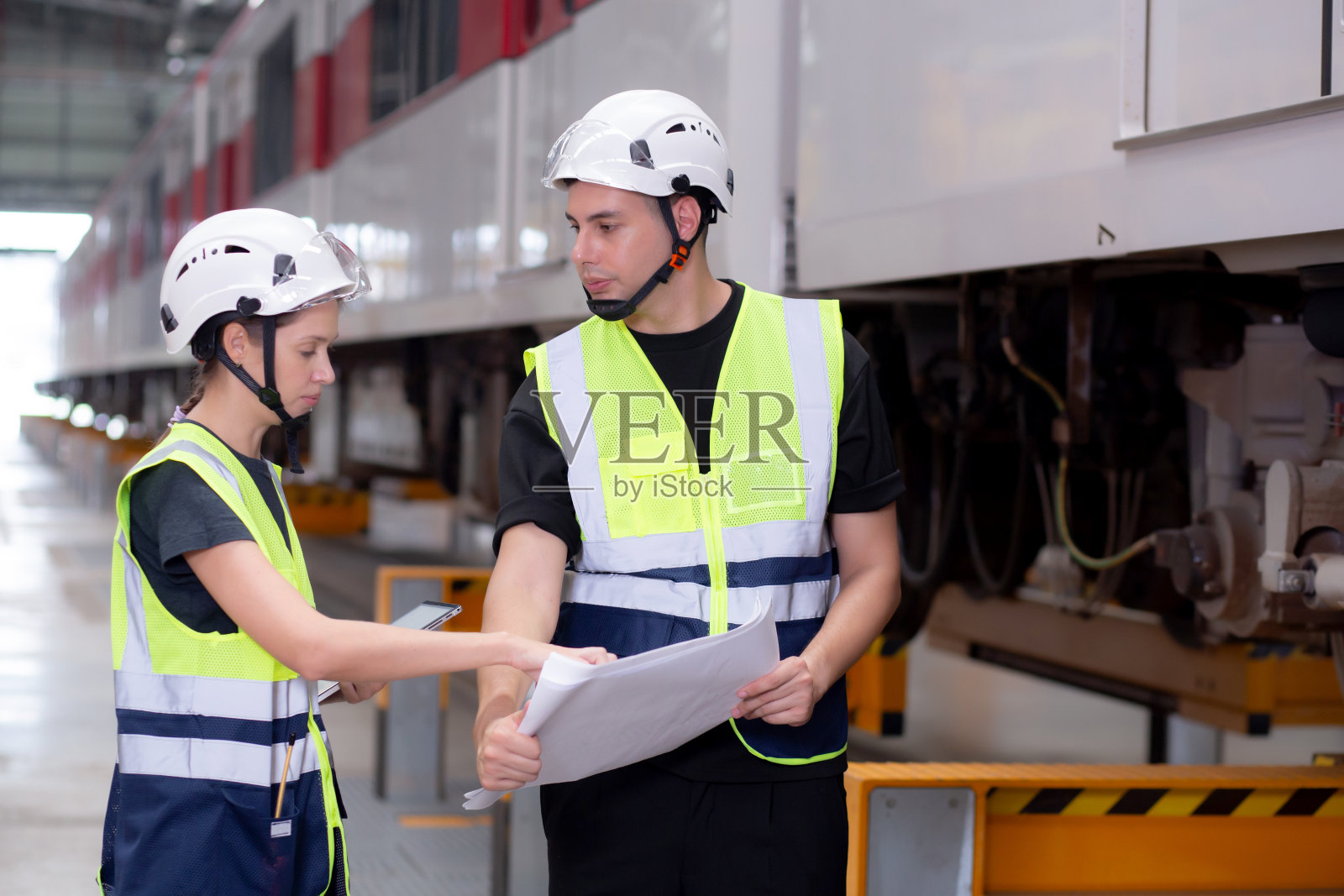 年轻的白人工程师或工人在车站、交通和基础设施的规划维护中查看蓝图和检查电动列车,检查员或技术人员检查运输。照片摄影图片