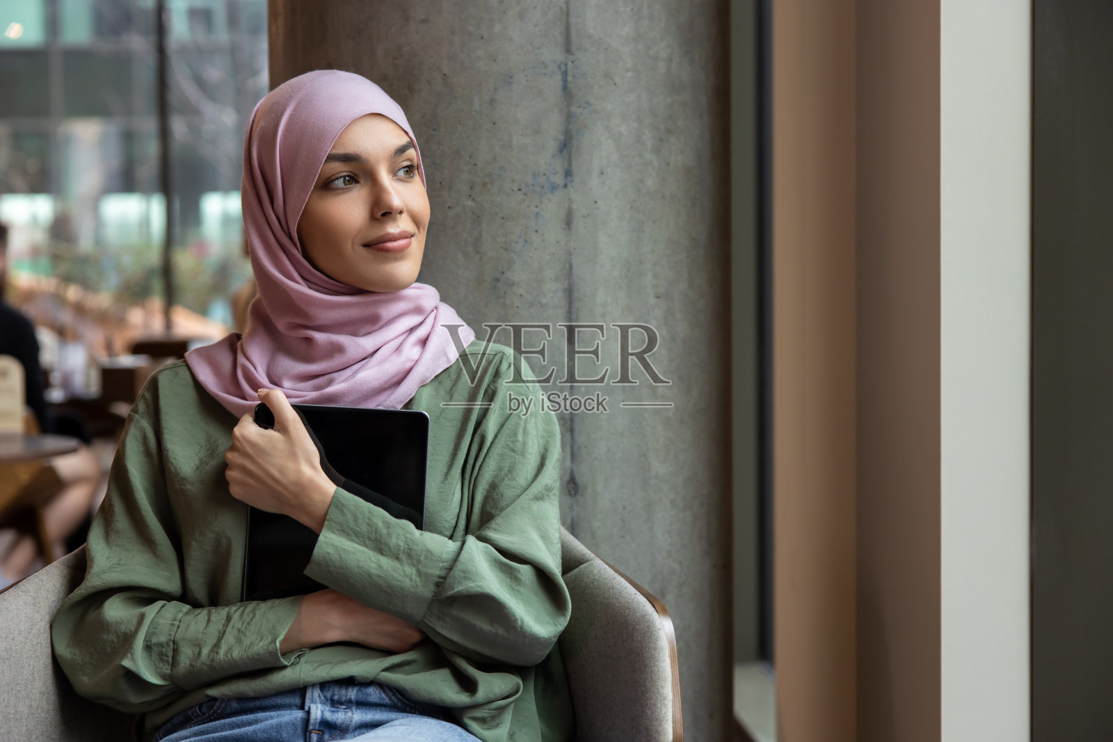 年轻女子穿着头巾,手里拿着笔记本电脑照片摄影图片