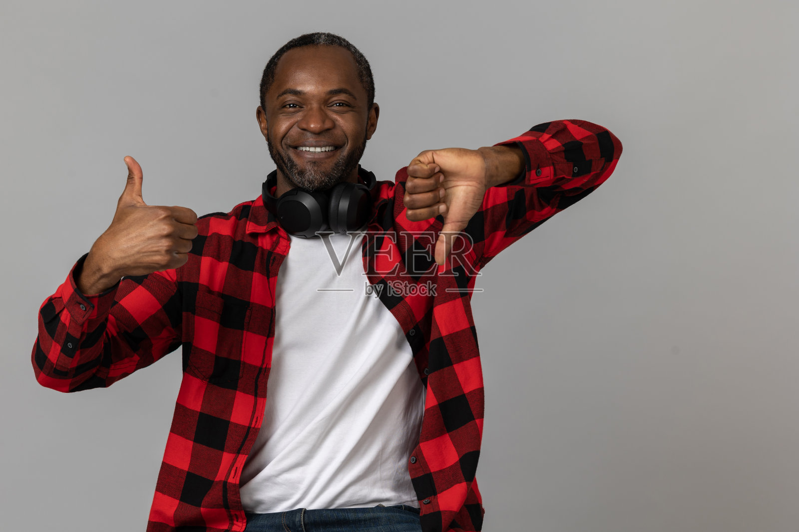 开朗的黑胡子男人穿着红色格子衬衫,摆出喜欢或不喜欢的姿势照片摄影图片