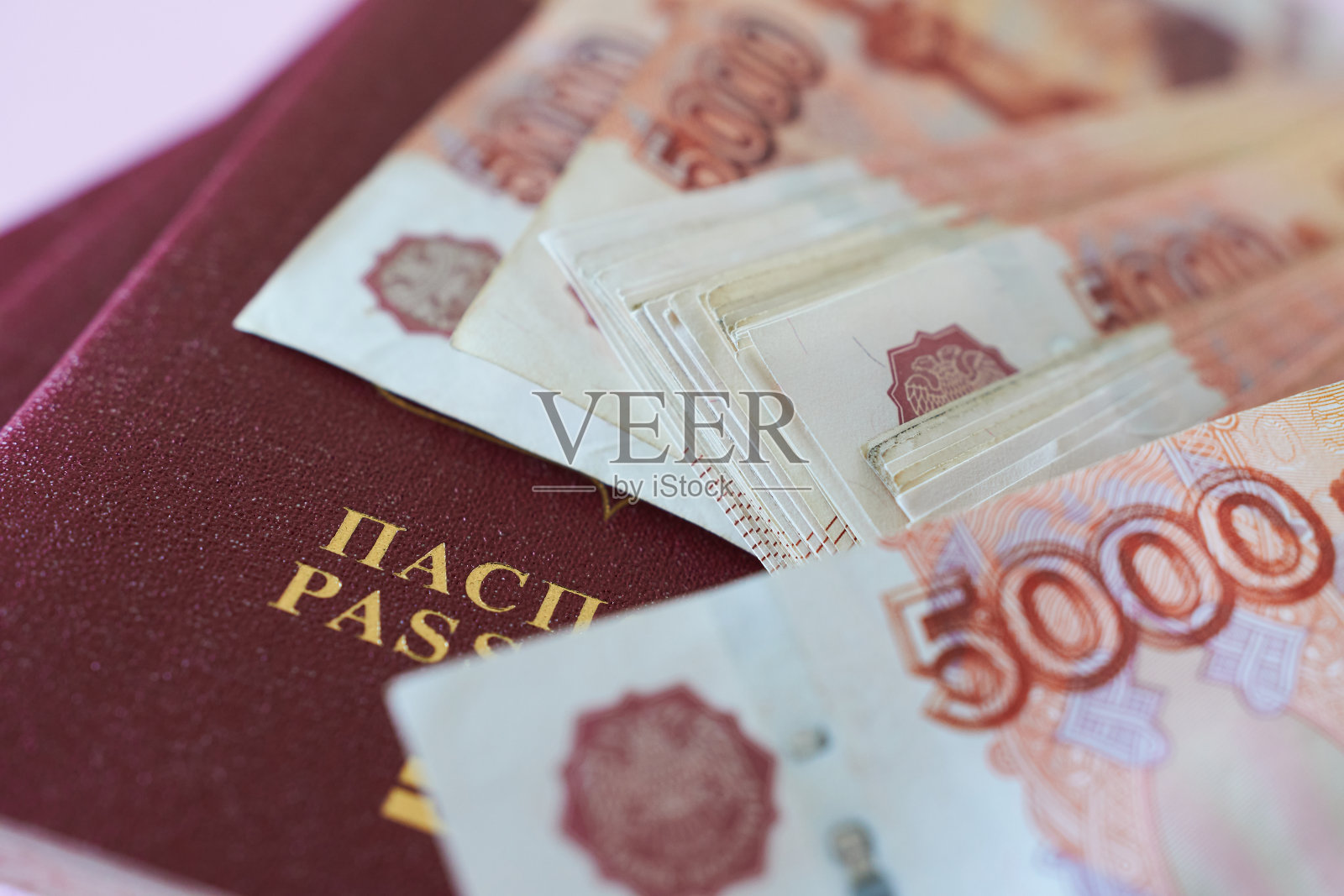 粉红色背景上的俄罗斯护照和钱的特写。照片摄影图片