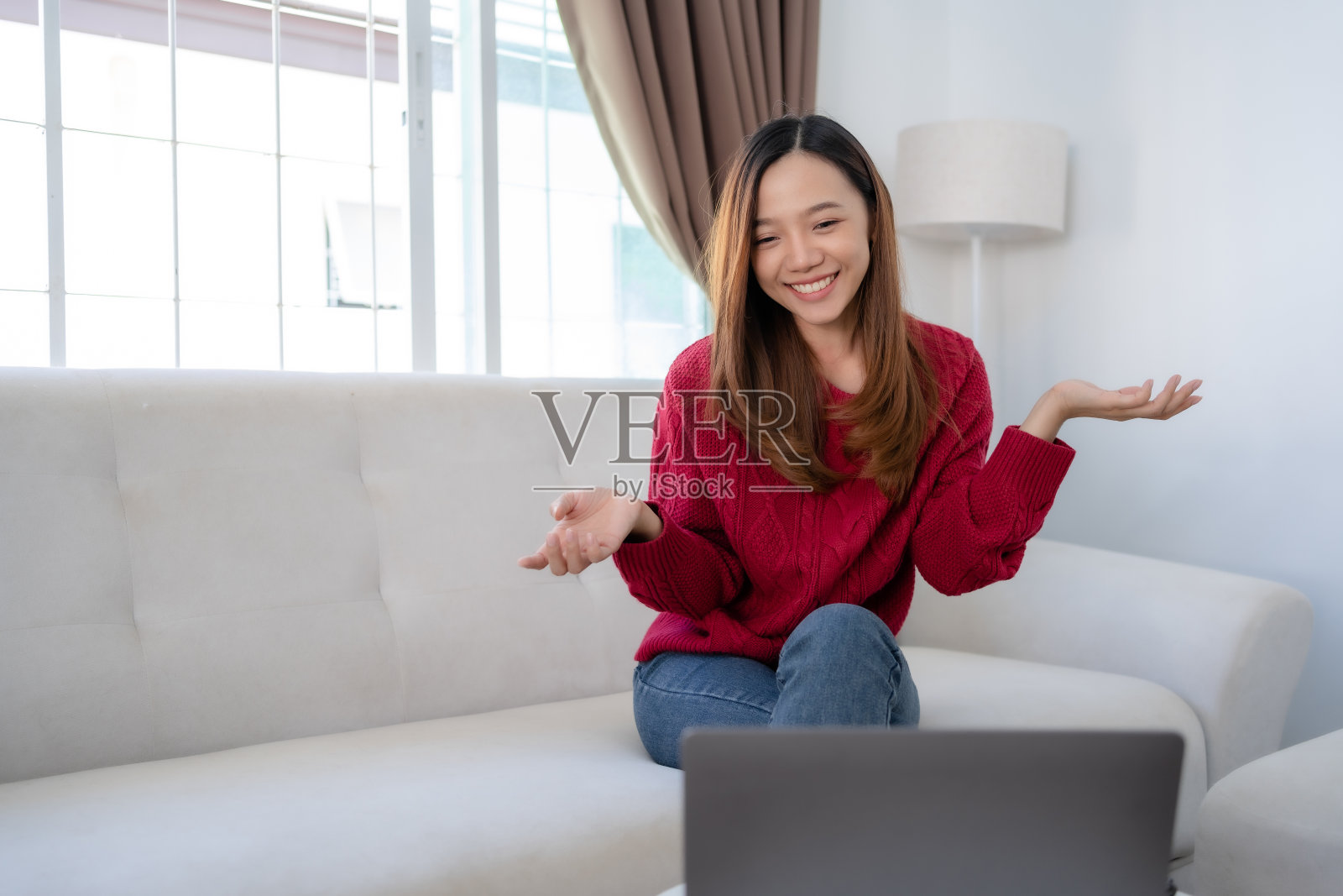 美丽的亚洲女人用笔记本电脑和朋友视频聊天,脸上带着微笑和快乐。照片摄影图片