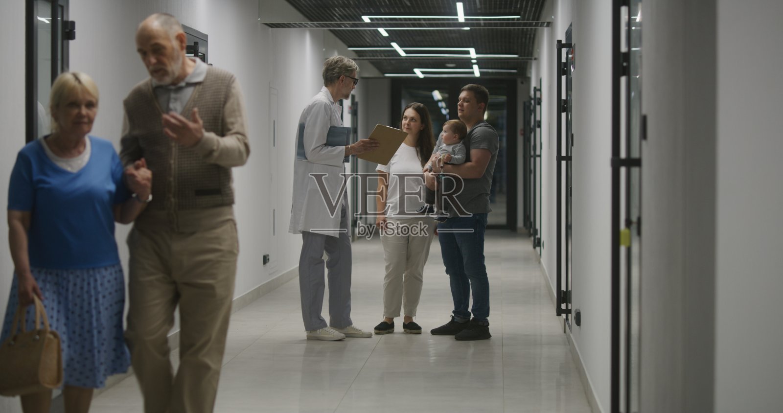医生和家人带着小孩站在医院走廊里照片摄影图片
