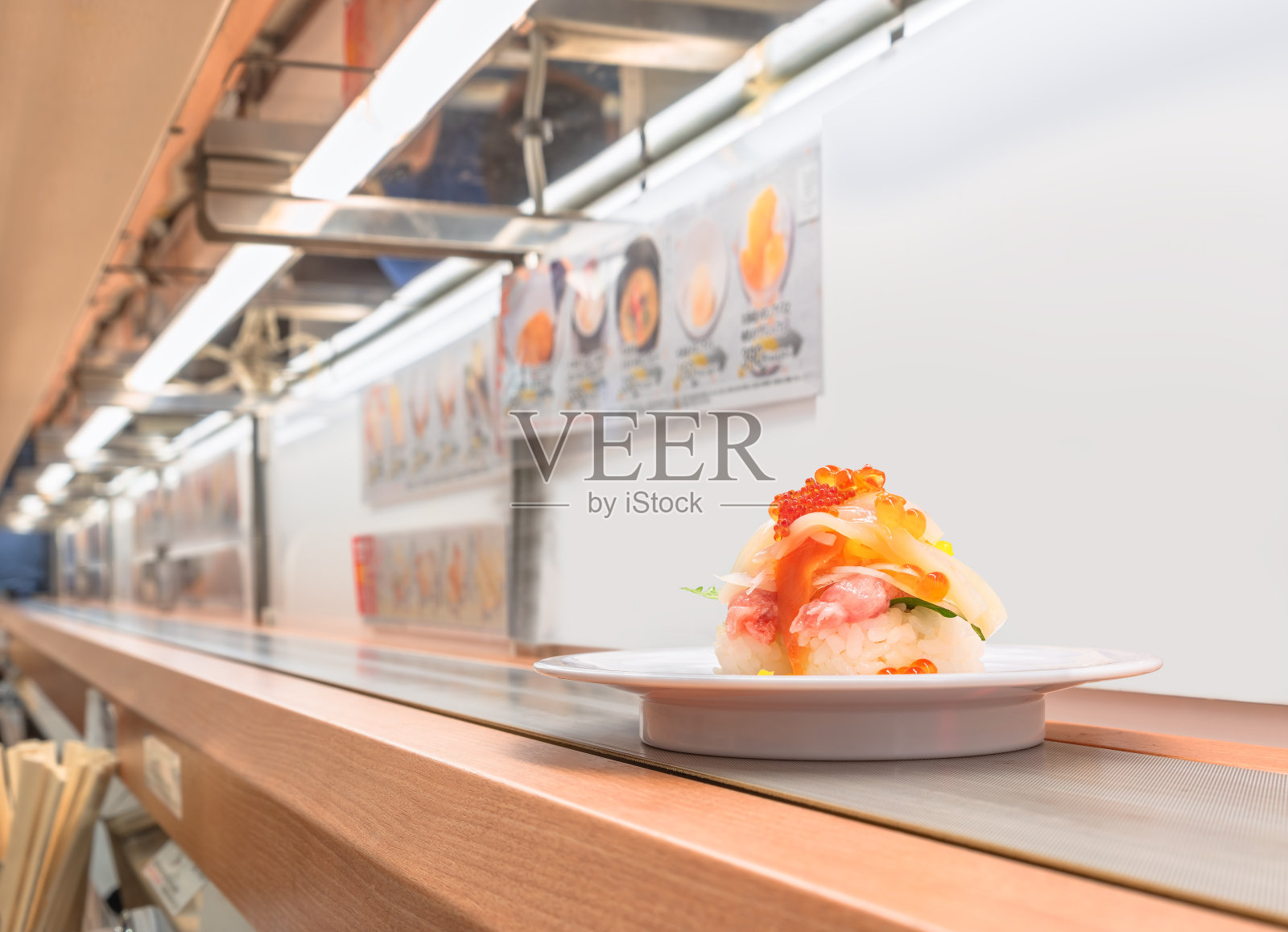 寿司传送带的微距镜头,一个盘子里放着寿司。照片摄影图片