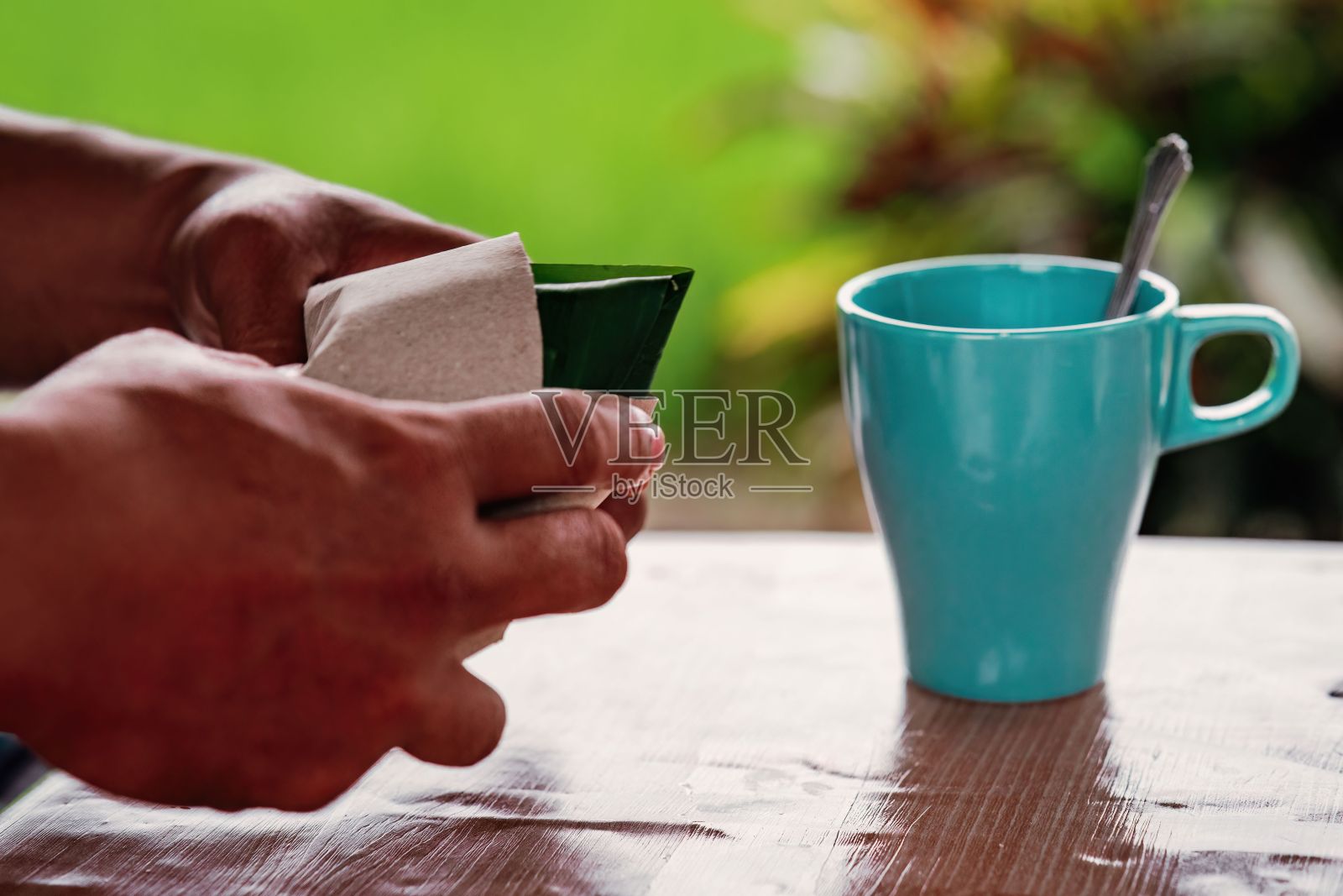 坐在户外木桌边享受热气腾腾的咖啡的人照片摄影图片