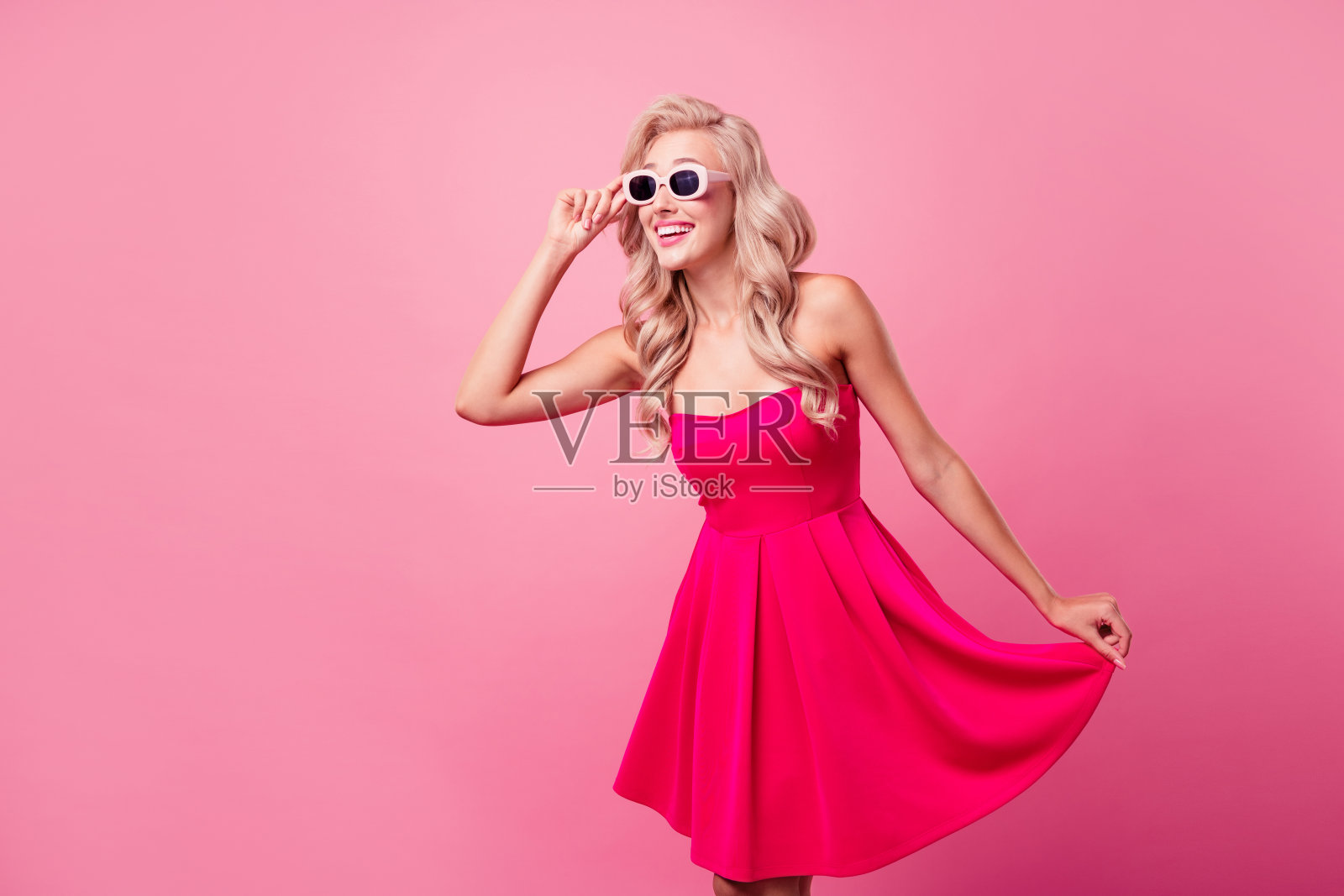 照片惊讶的积极可爱的人手臂触摸太阳镜空白的空间,并隔离在粉红色的背景照片摄影图片