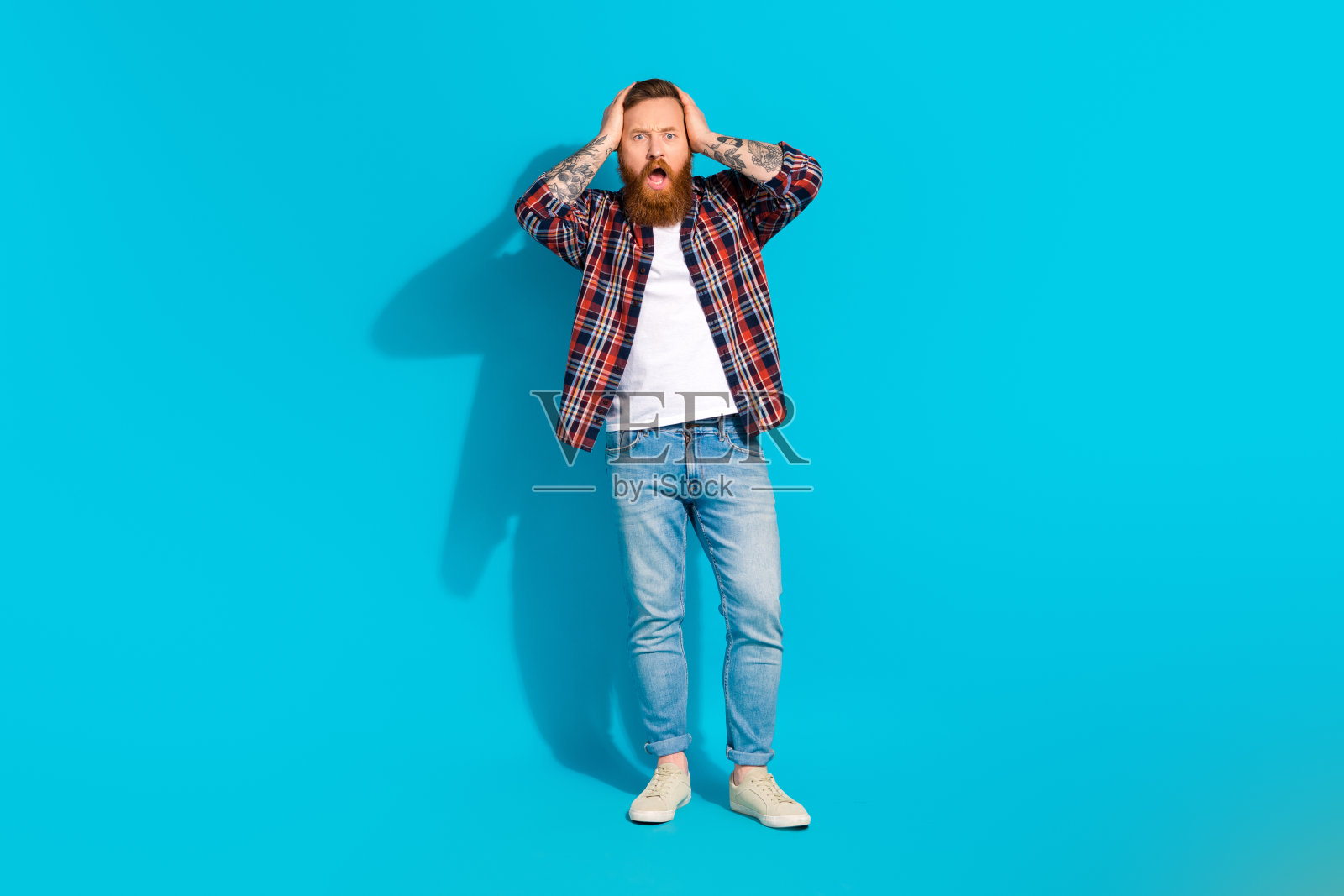 手抱头、神情困惑的中年男人,蓝色背景照片摄影图片