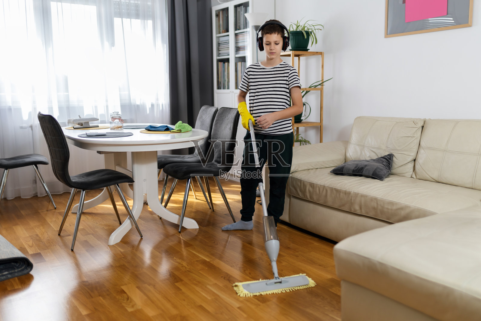 孩子一边打扫地板一边听音乐。照片摄影图片