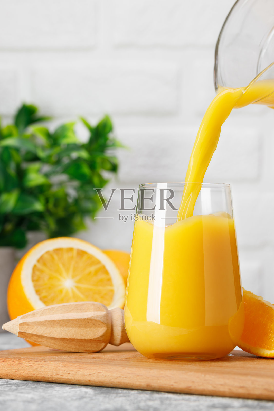 橙汁从桌上的水壶里倒进玻璃杯照片摄影图片