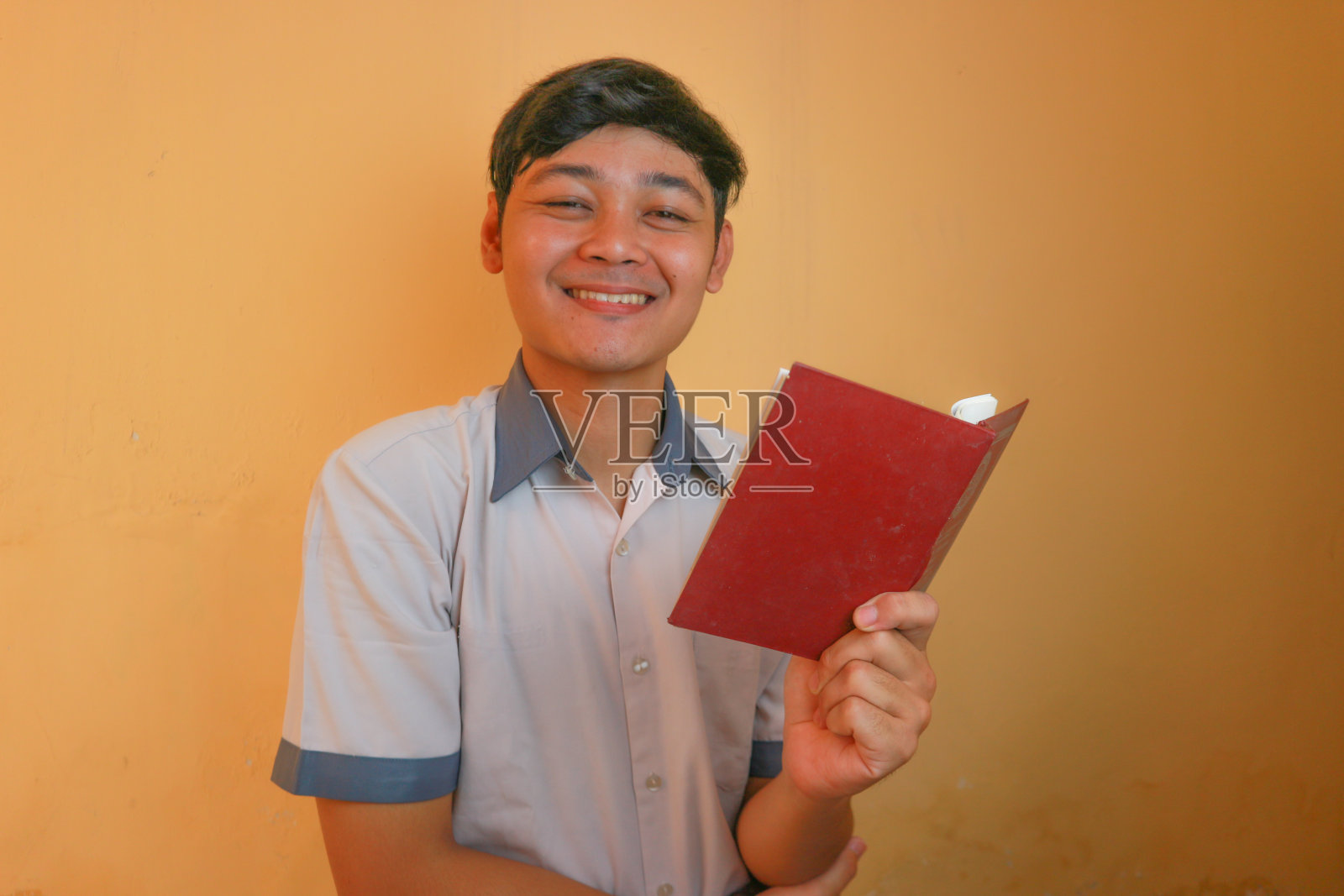 印尼高中男生穿灰色和白色的校服。孤立在黄色背景上,有着非常多样的表情照片摄影图片