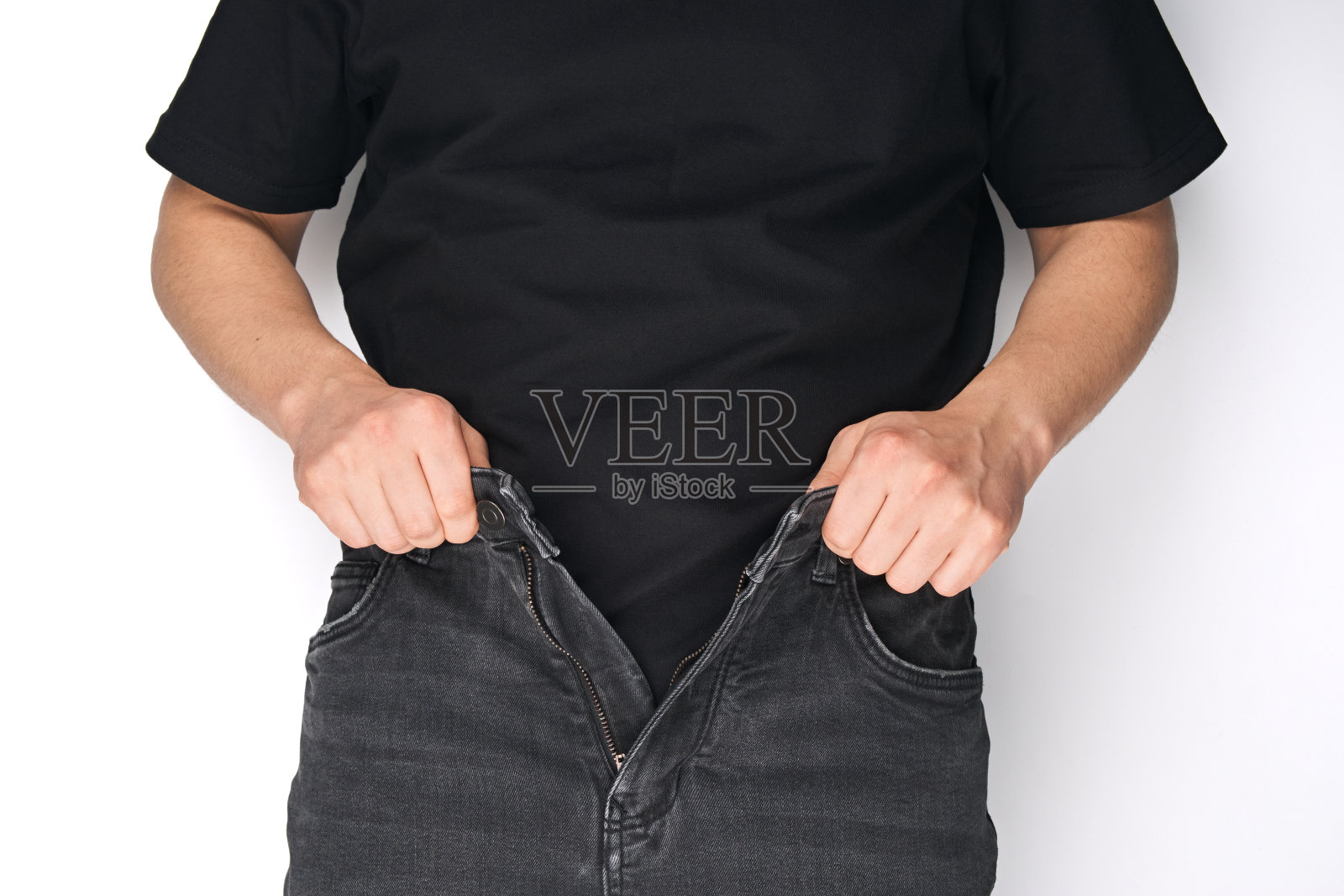 一个穿着黑色牛仔裤的男人系上腰带。牛仔裤的腰带。黑色皮带。扣。照片摄影图片