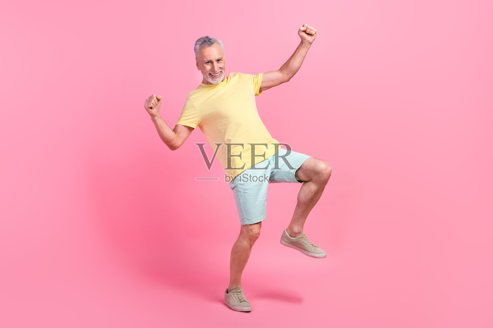 全身照片穿黄色t恤蓝色短裤老人庆祝他的暑假孤立在粉红色的背景照片摄影图片