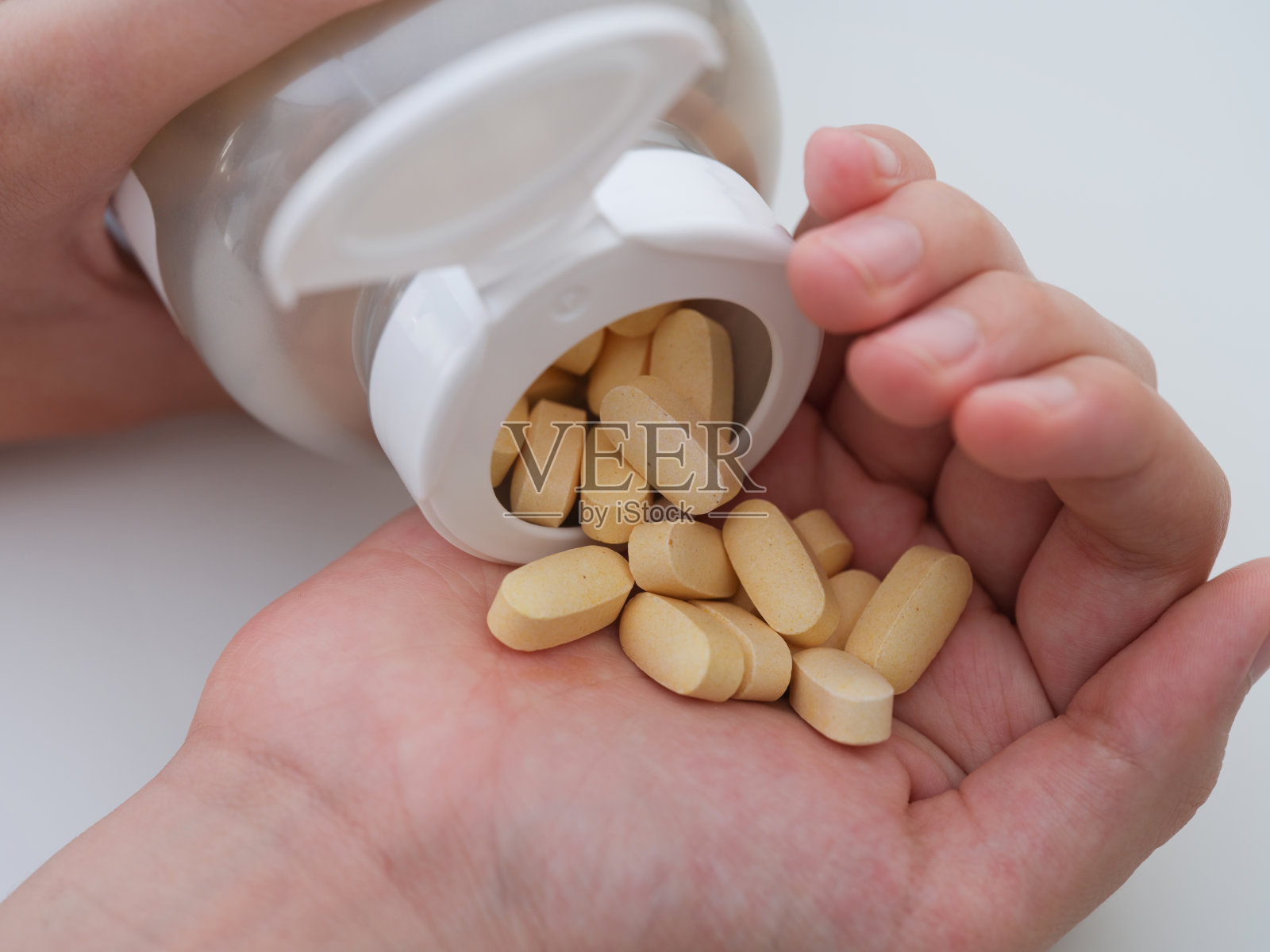 一个年轻人把牛磺酸镁片从瓶子里倒到他的手掌里照片摄影图片