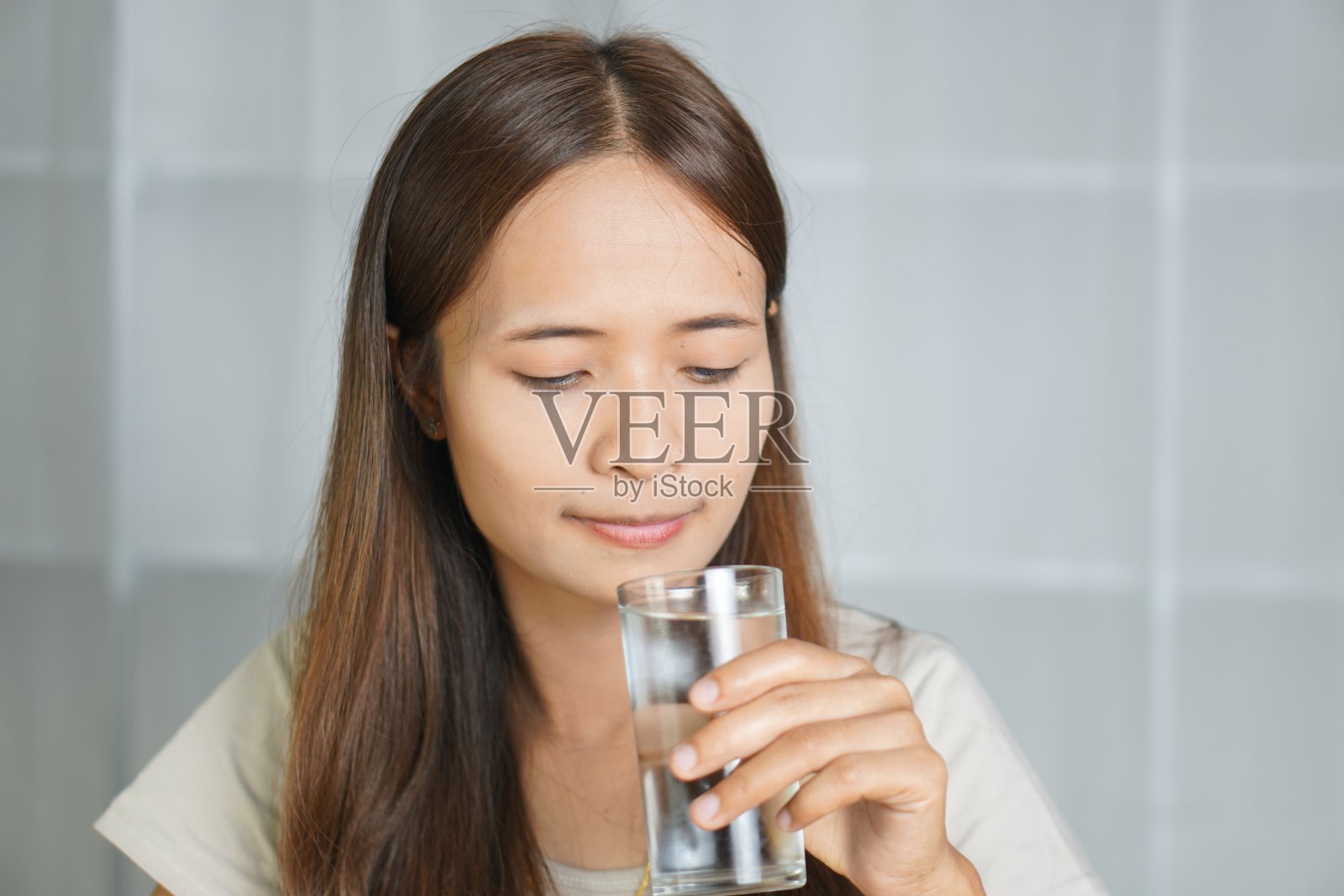 亚洲女人喝着水,在家工作照片摄影图片