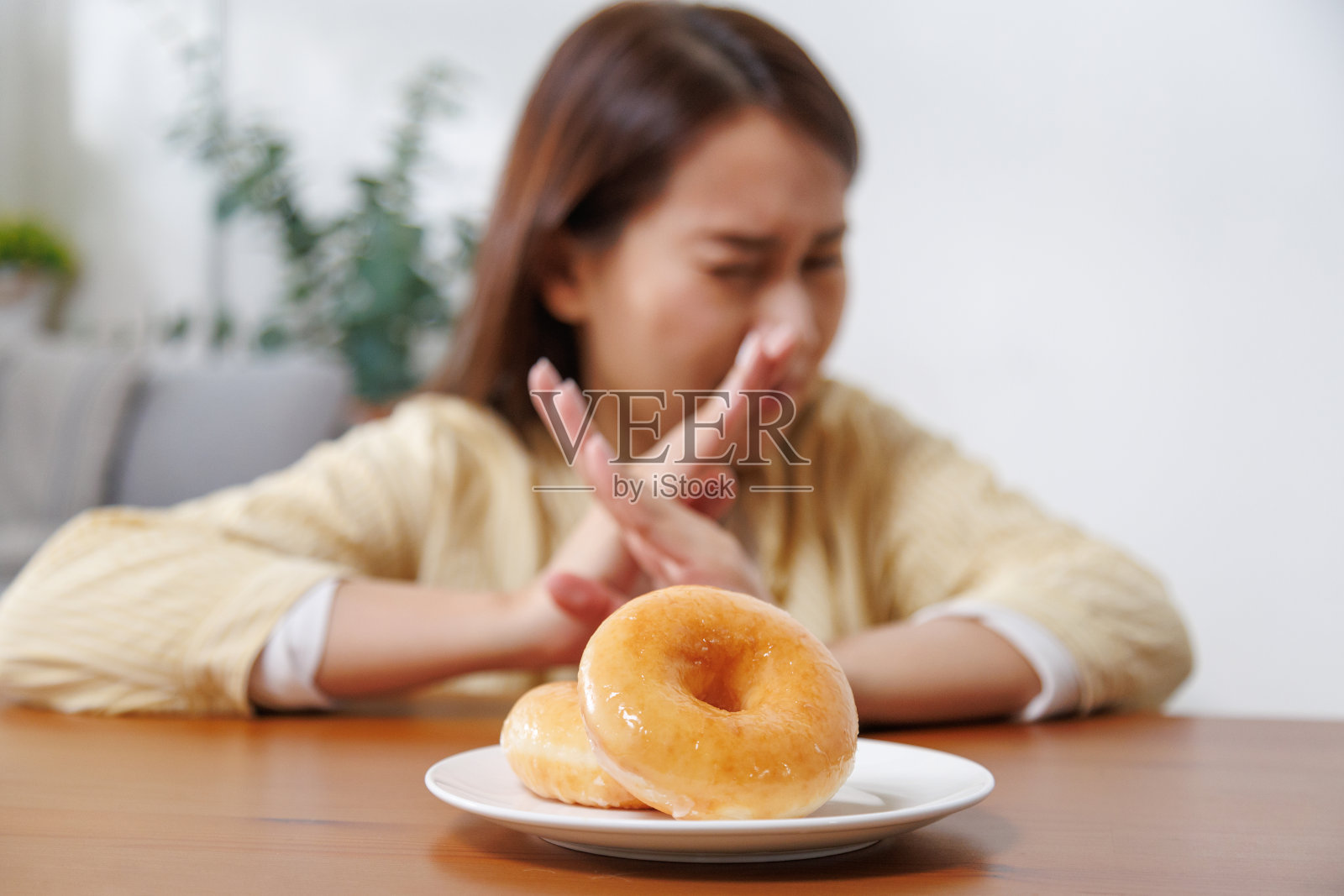 亚洲女性拒绝吃含有反式脂肪的甜甜圈。节食女人不吃不健康的食物。健康生活理念。照片摄影图片