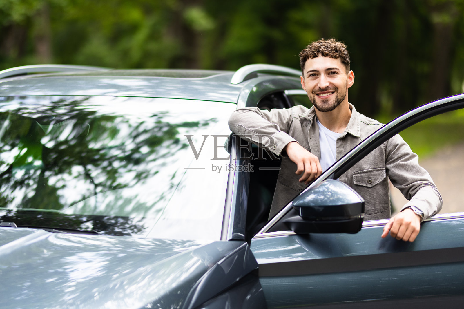 一个微笑的男人站在他的车旁边照片摄影图片