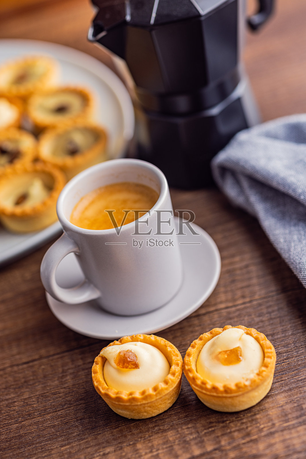 甜tarlets。美味的迷你蛋挞。迷你派,奶油和咖啡杯放在厨房桌子上。照片摄影图片