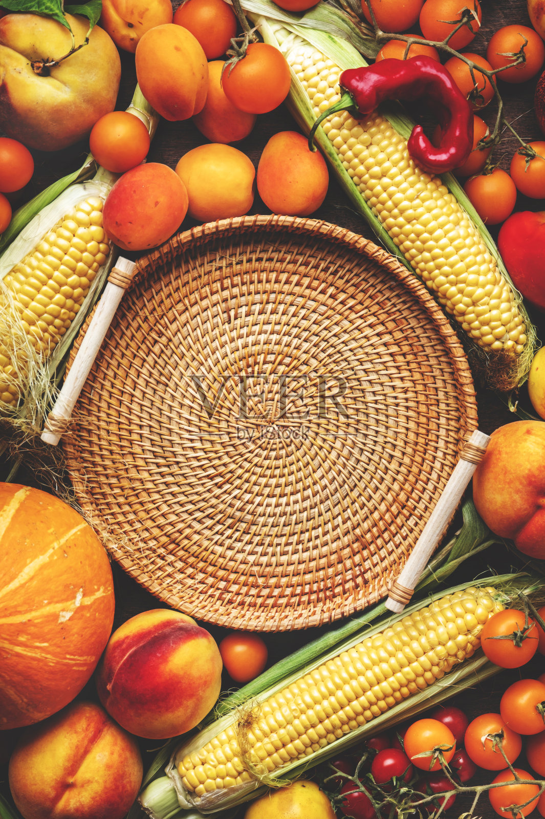 秋天五颜六色的蔬菜水果套装:杏子、西红柿、南瓜、辣椒、玉米等和空柳条托盘放在质朴的木制背景上,俯视图,复制空间照片摄影图片