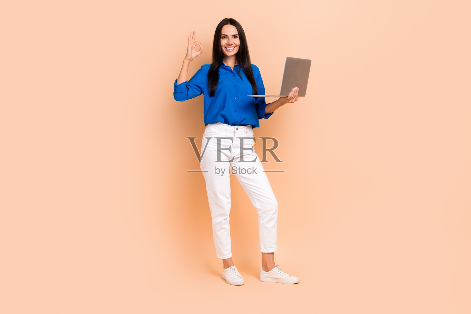 迷人的积极的女士的照片穿着时尚的蓝色衬衫手臂显示好的标志好质量现代设备孤立米色背景照片摄影图片