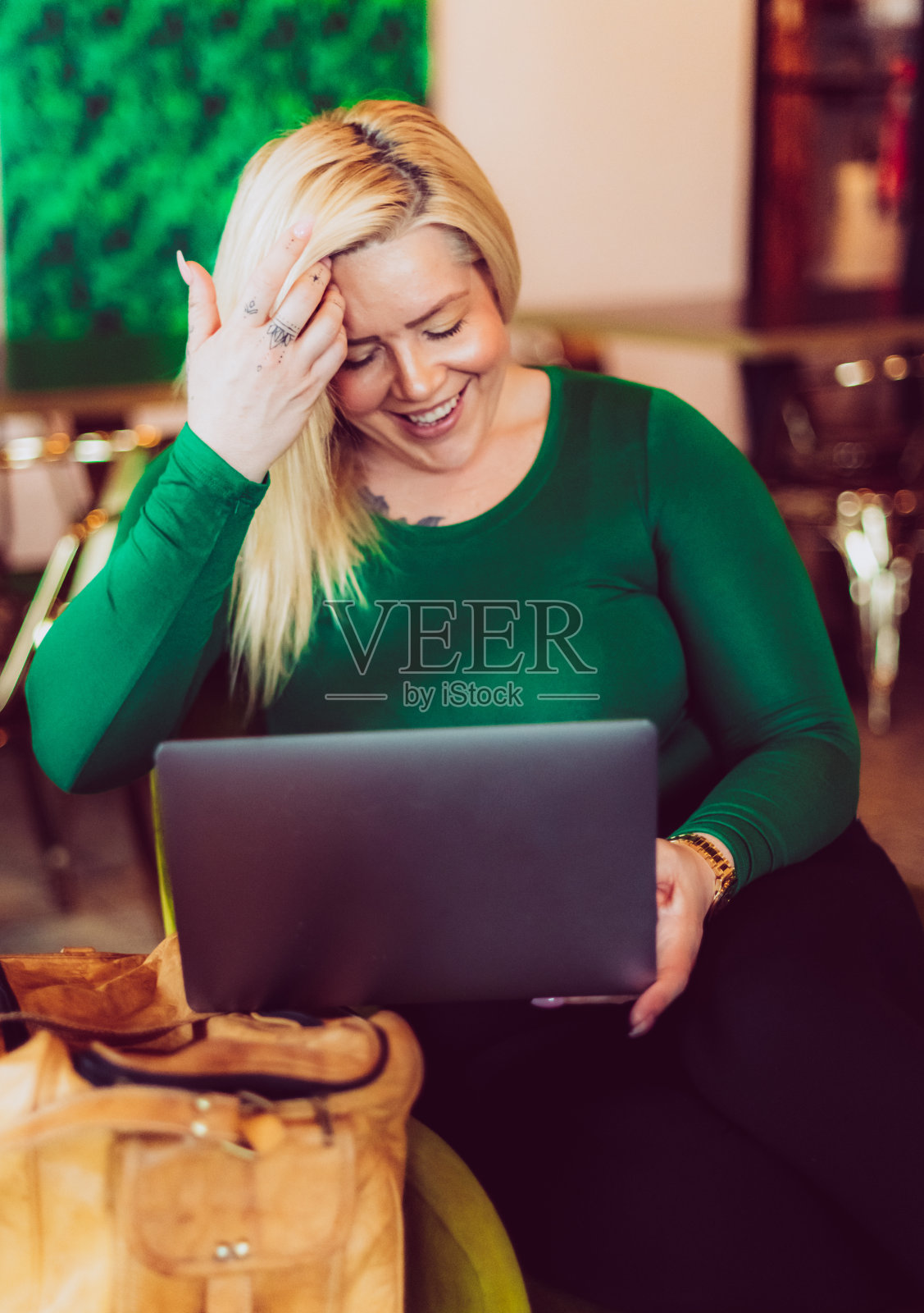 40多岁的金发美女穿着翠绿色衣服在室内使用笔记本电脑照片摄影图片