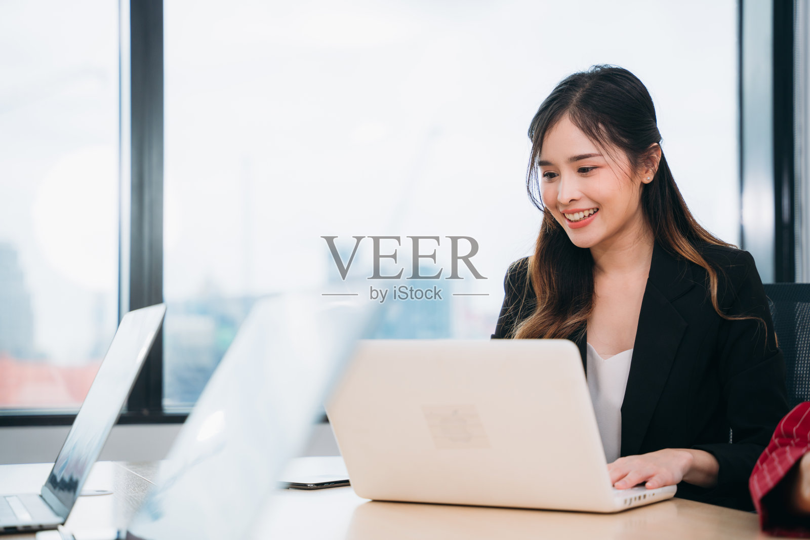 女商人在办公室与电脑讨论和会面的肖像。微笑的美女坐在工作场所前。在会议中使用电脑。照片摄影图片