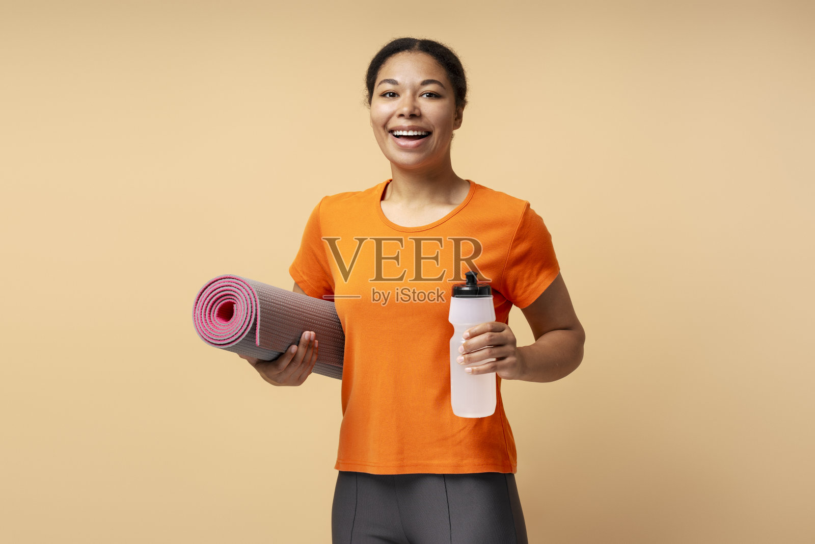 非裔美国人快乐微笑的女人拿着健身瑜伽垫望向别处照片摄影图片