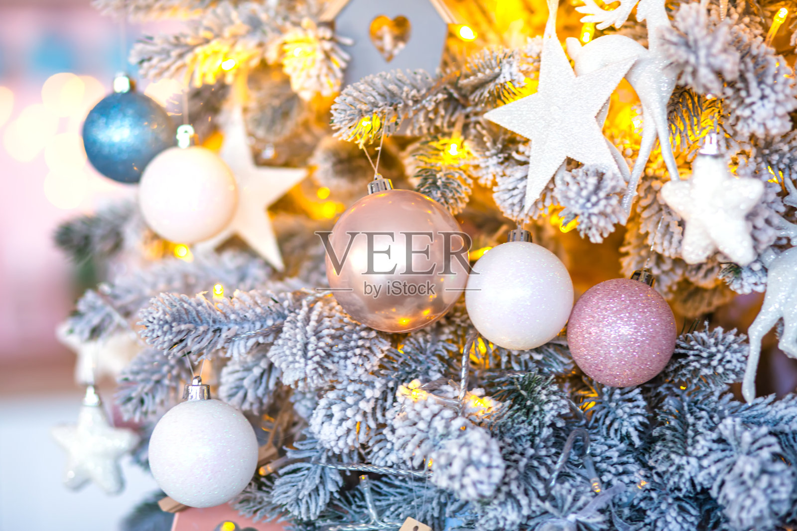 光芒四射的圣诞冷杉穿着精美的蓝色和玫瑰色的小装饰品,背景闪闪发光照片摄影图片