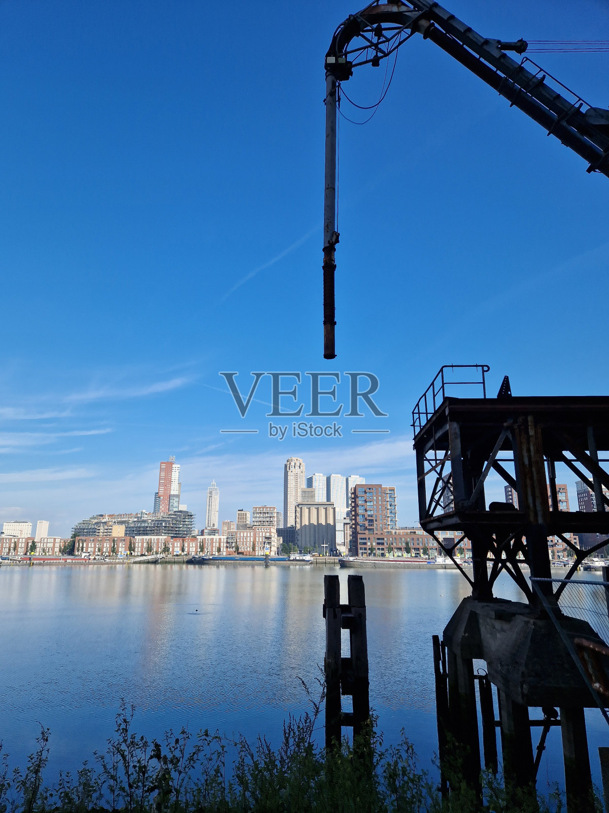 工业起重机和设备,背景是鹿特丹的天际线,映照在默兹河的水中照片摄影图片