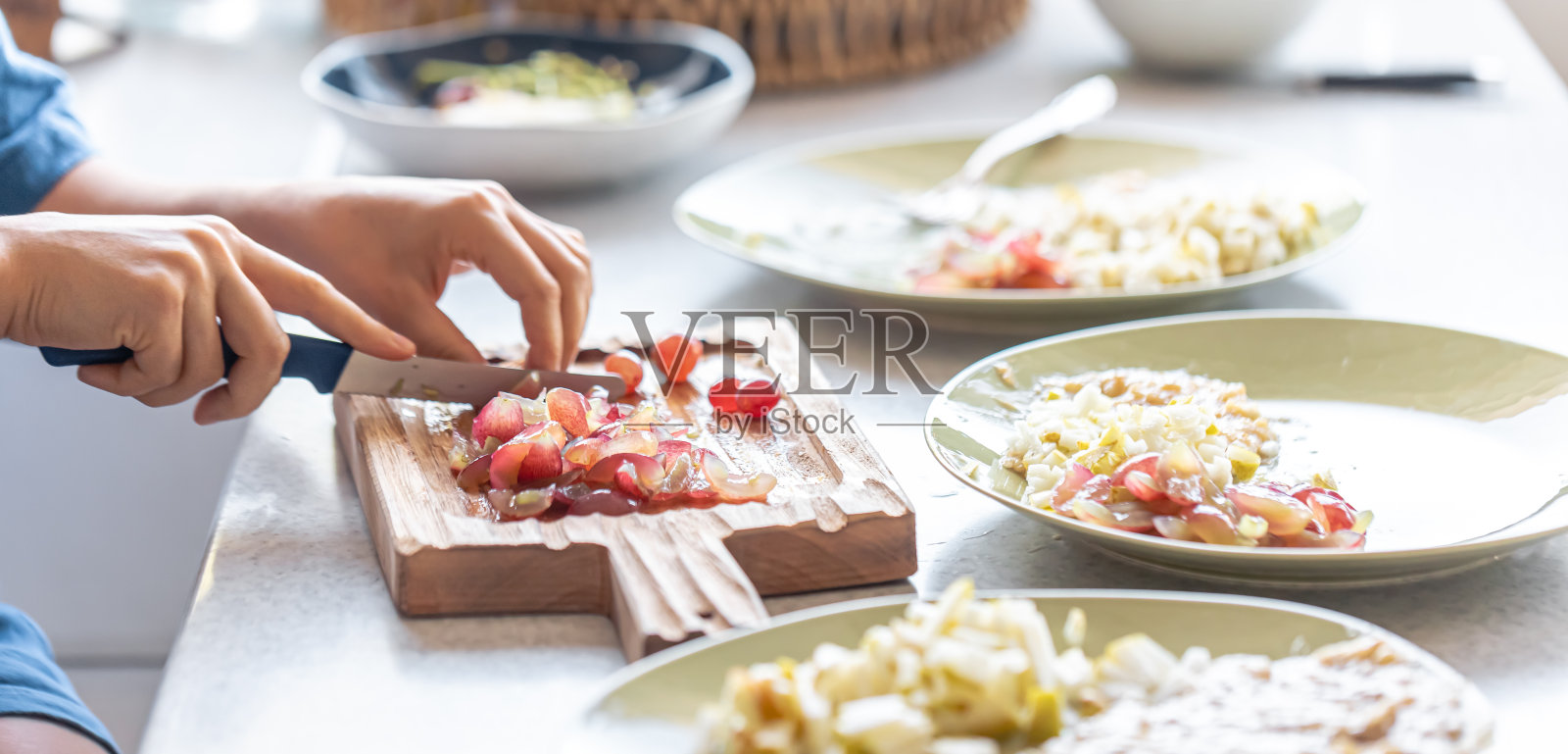 一个女人在砧板上切葡萄。照片摄影图片