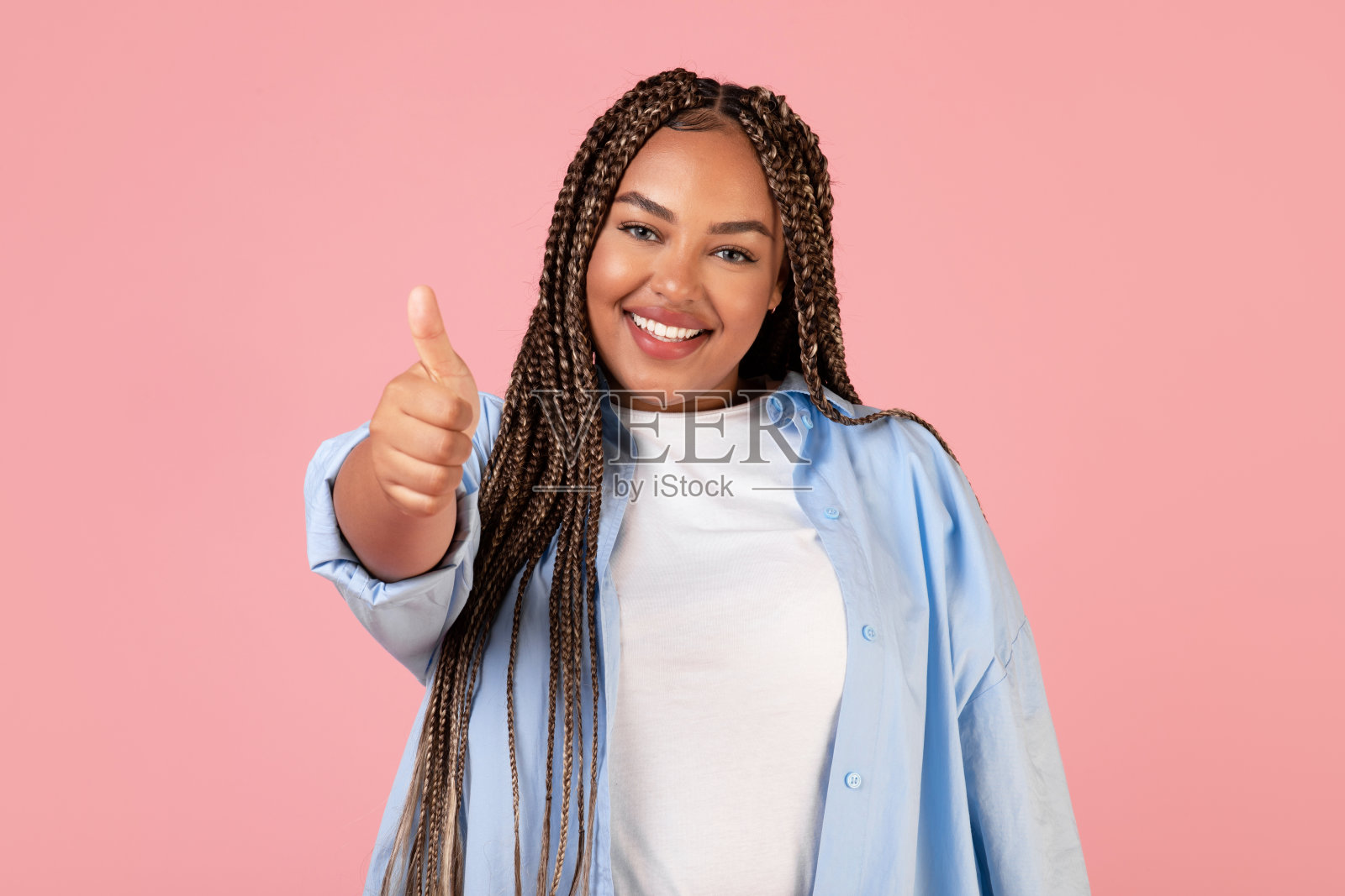 快乐的黑人女士在粉红色的背景上竖起大拇指照片摄影图片