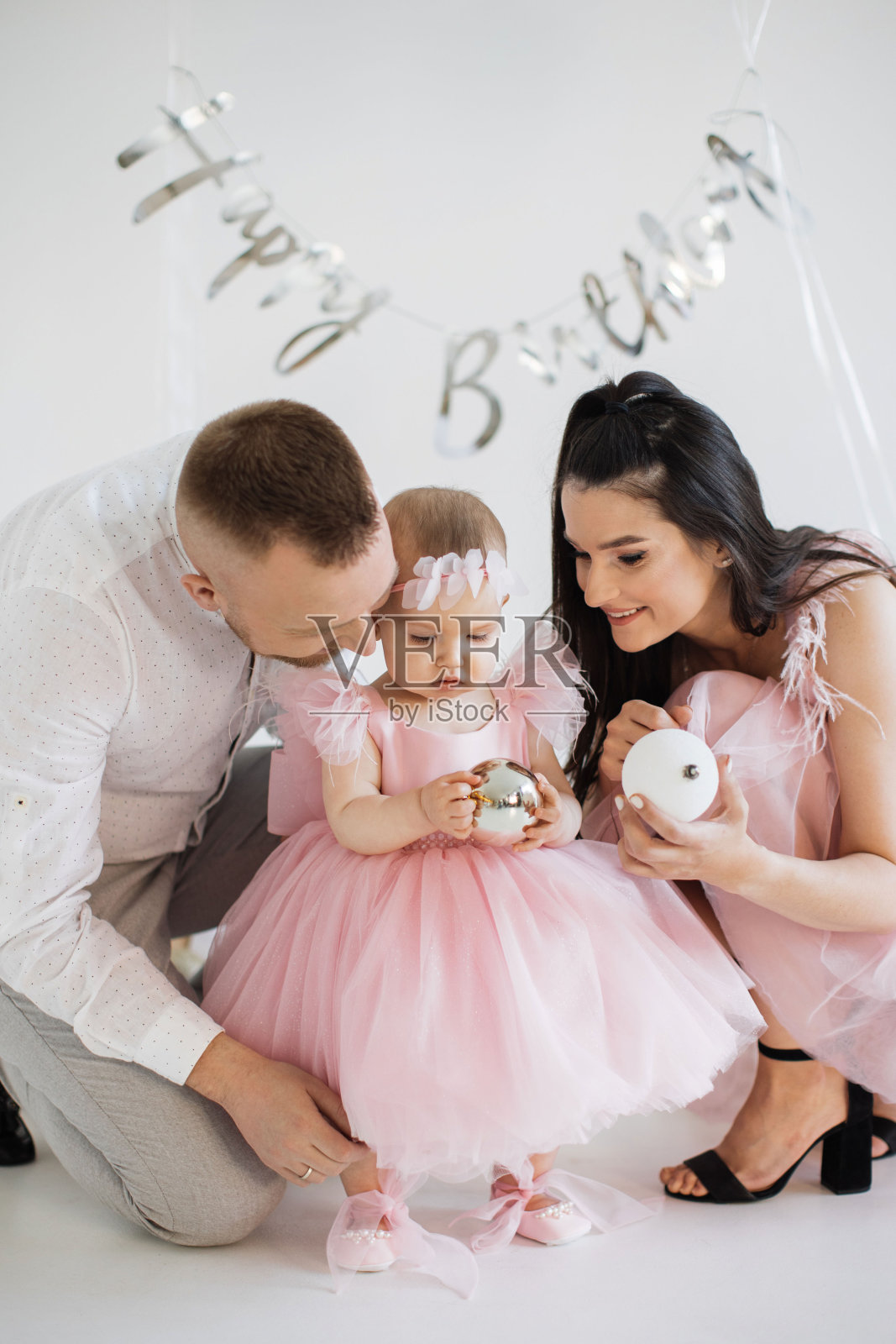 欢快的父母和女儿在生日装饰中玩耍照片摄影图片