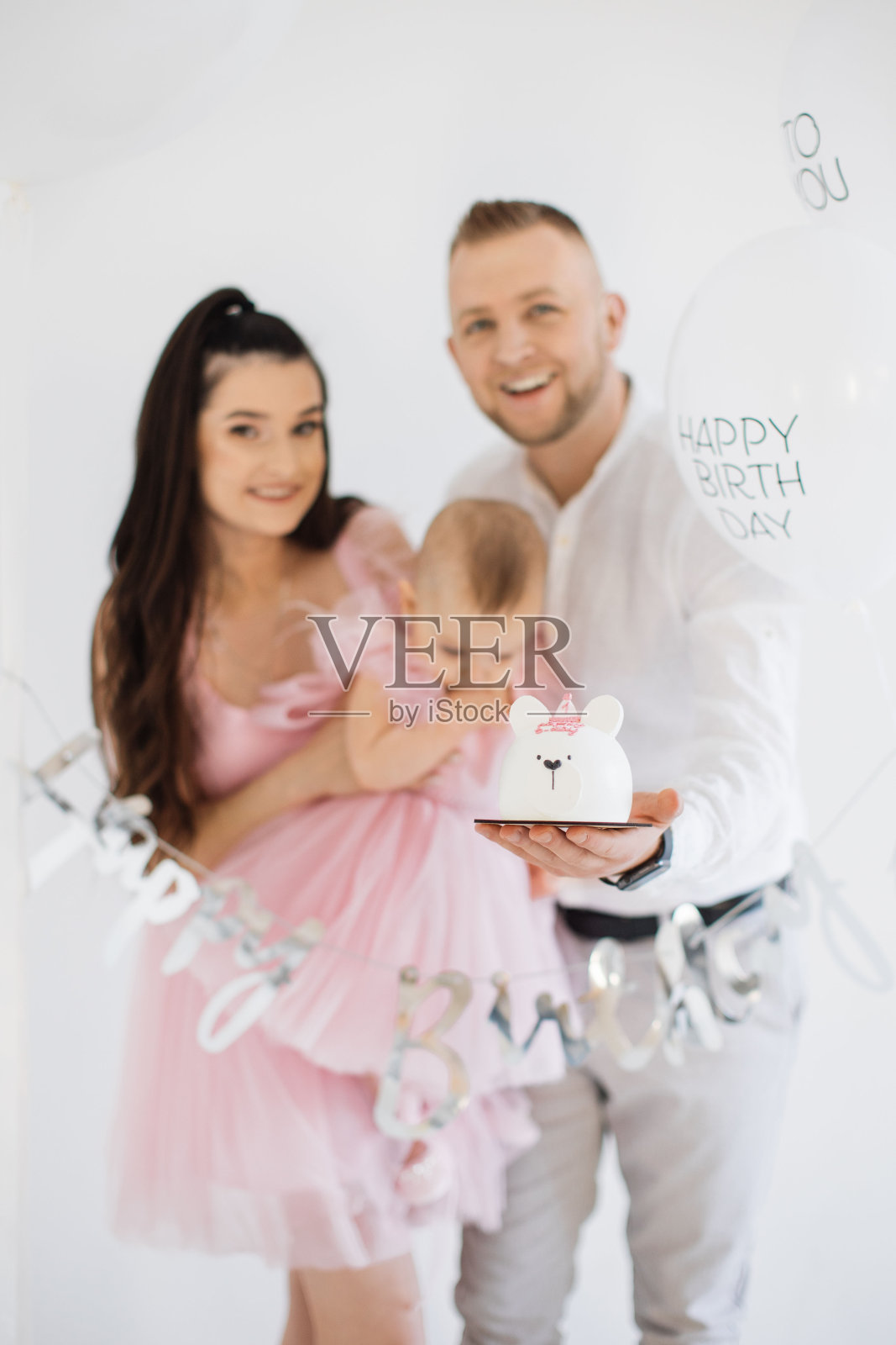 快乐的家庭和可爱的宝宝抱着生日蛋糕在工作室照片摄影图片